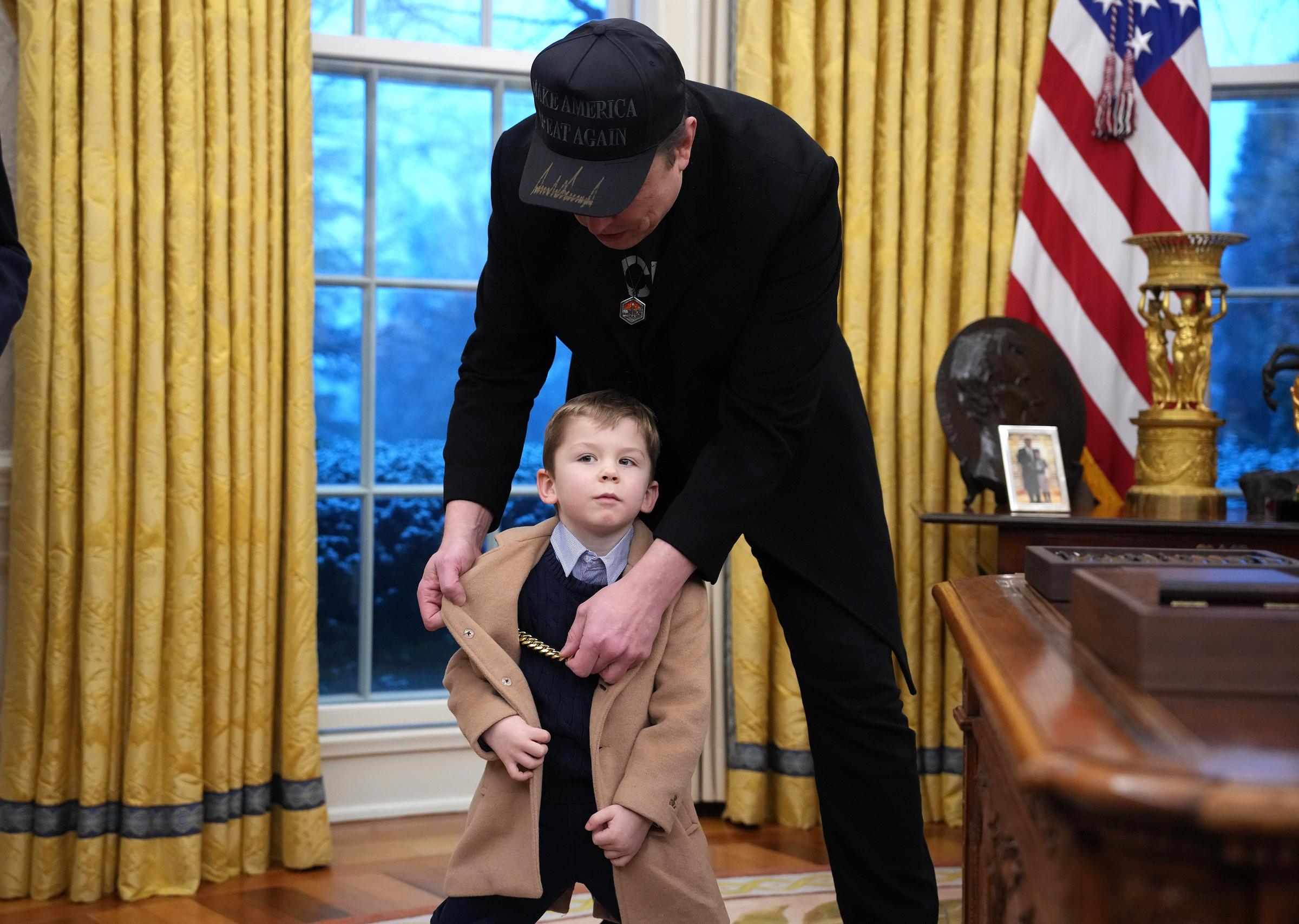 Elon Musk adjusts Xs jacket. | Source: Getty Images