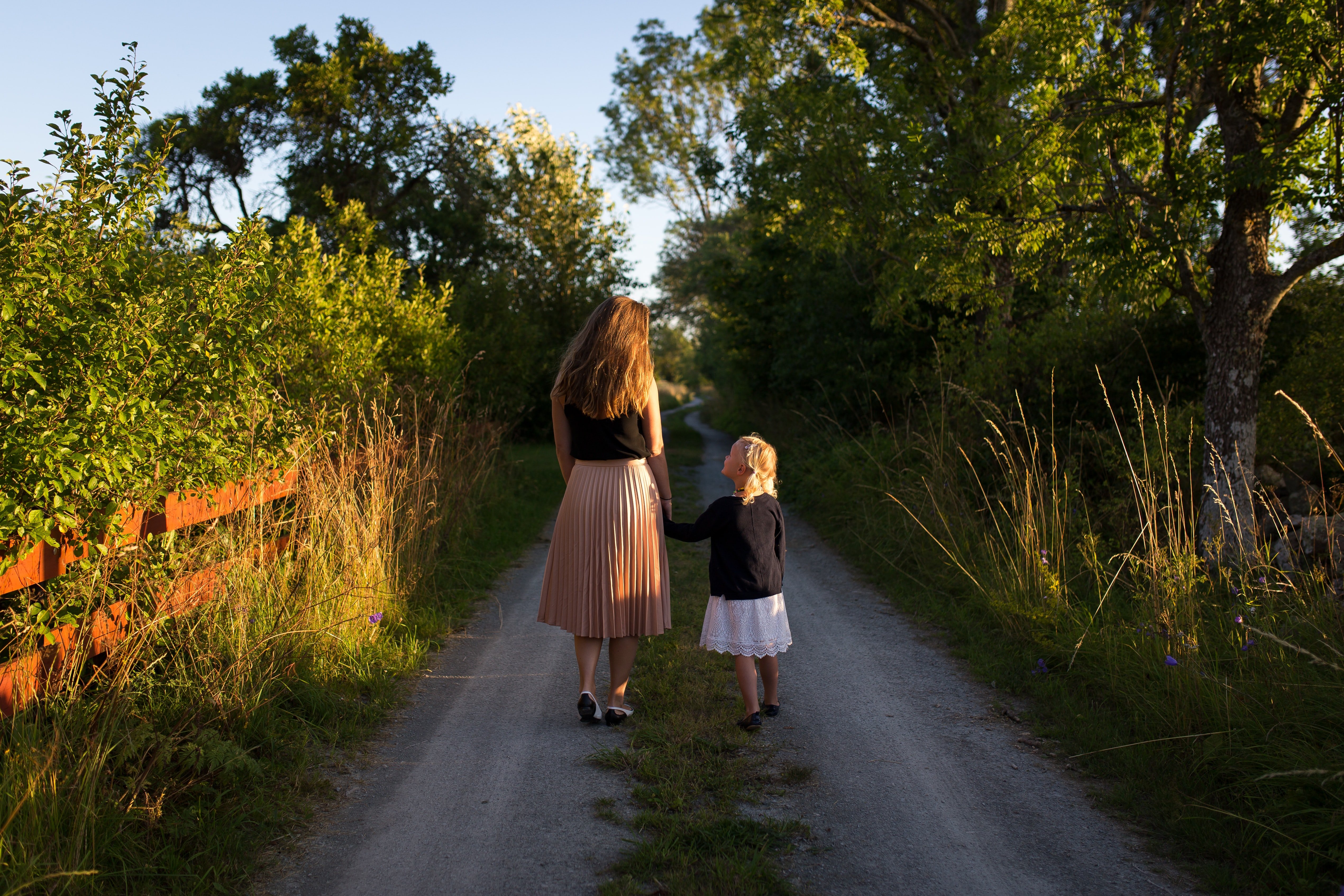 Mujer y niña de espaldas en un camino rural. | Foto: Unsplash