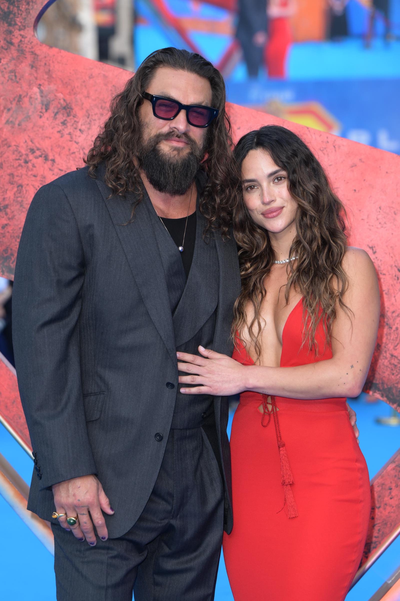 Jason Momoa and Adria Arjona attend the Supergirl fan event in London's Leicester Square on June 18, 2026. The couple appeared relaxed and affectionate on the blue carpet, but it was another family photo from the evening that soon sparked a wave of online comparisons. | Source: Getty Images