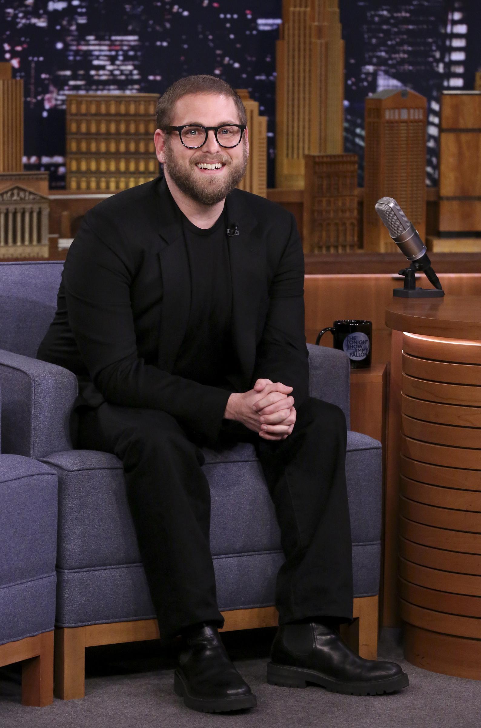 Jonah Hill returned to late-night television for an appearance on "The Tonight Show Starring Jimmy Fallon" on October 11, 2018. Dressed entirely in black, with closely cropped hair, a full beard, and thick-framed glasses, the actor smiled from the guest chair while displaying the leaner physique he had maintained. By this point, Hill's appearance had changed considerably from the curly-haired, fuller-figured look associated with the beginning of his career.