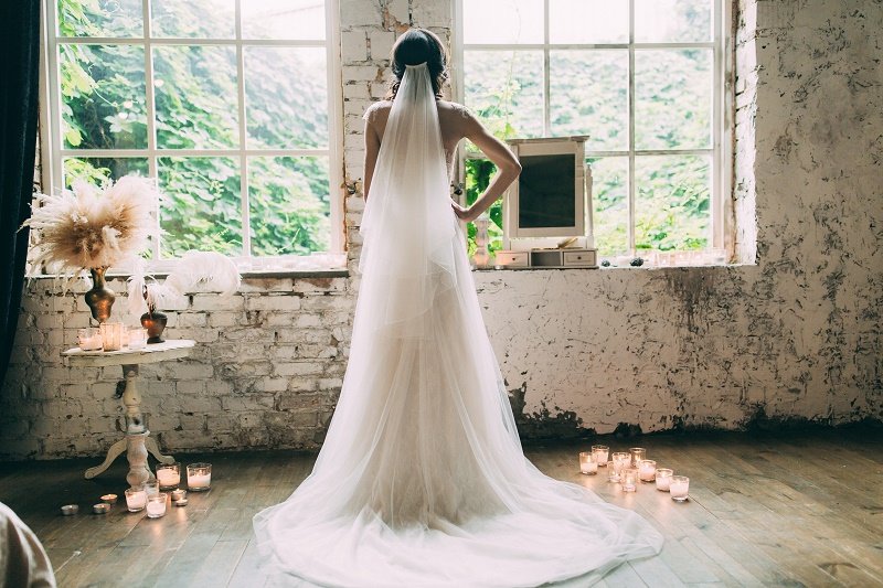 A woman wearing a wedding dress with a long veil hanging from her head | Image: Shutterstock.