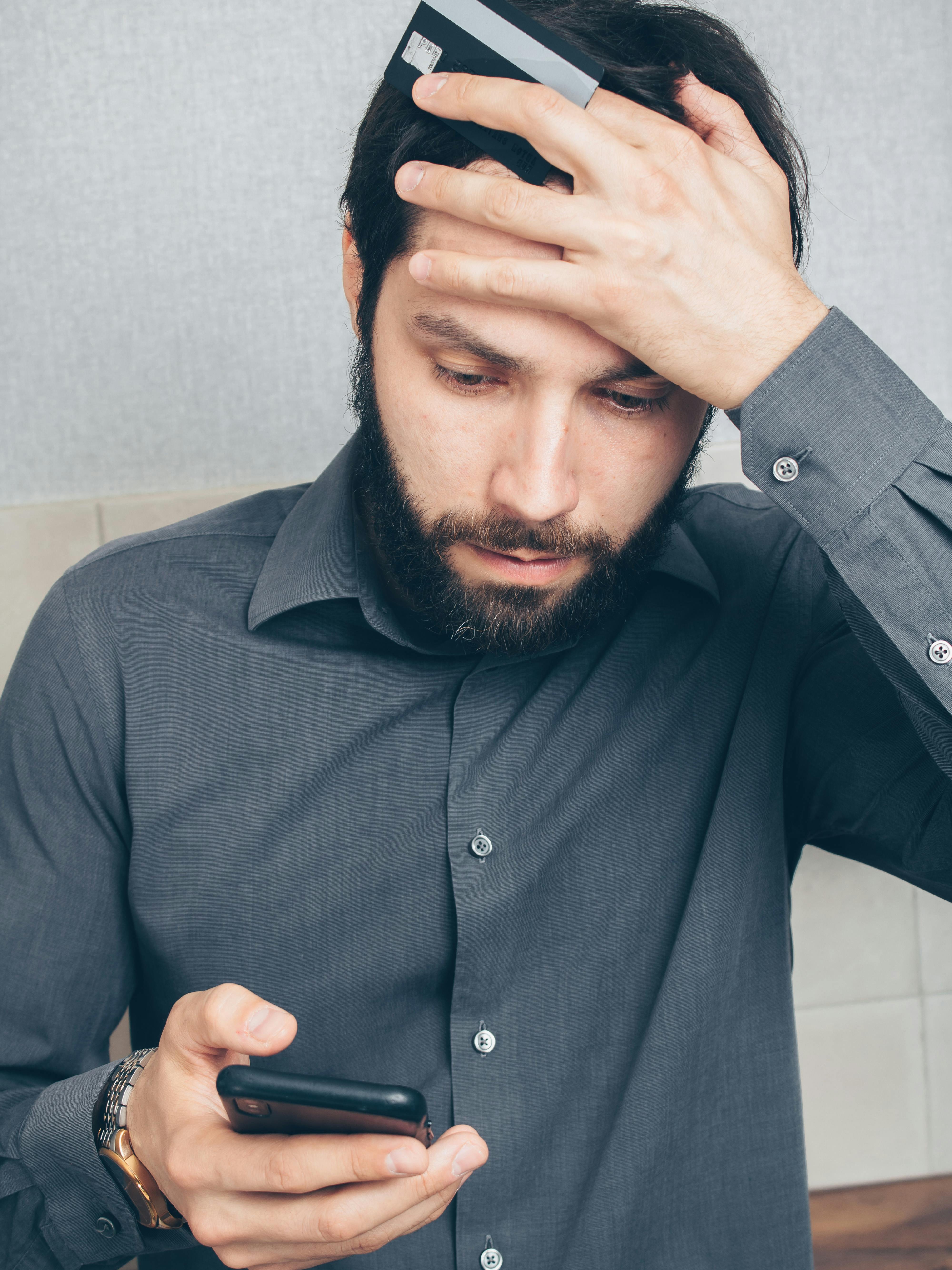 A shocked man looking at his phone in his kitchen | Source: Pexels