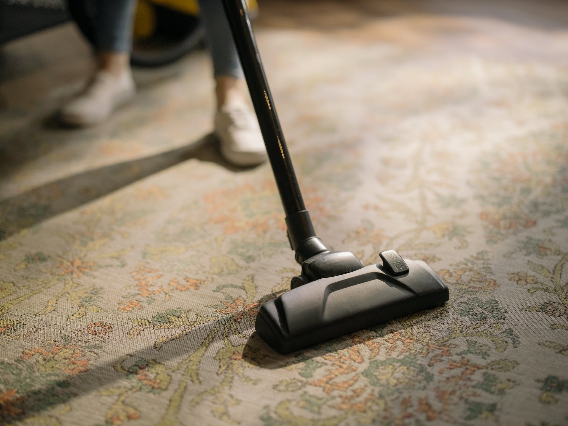 A person vacuuming a rug | Source: Pexels