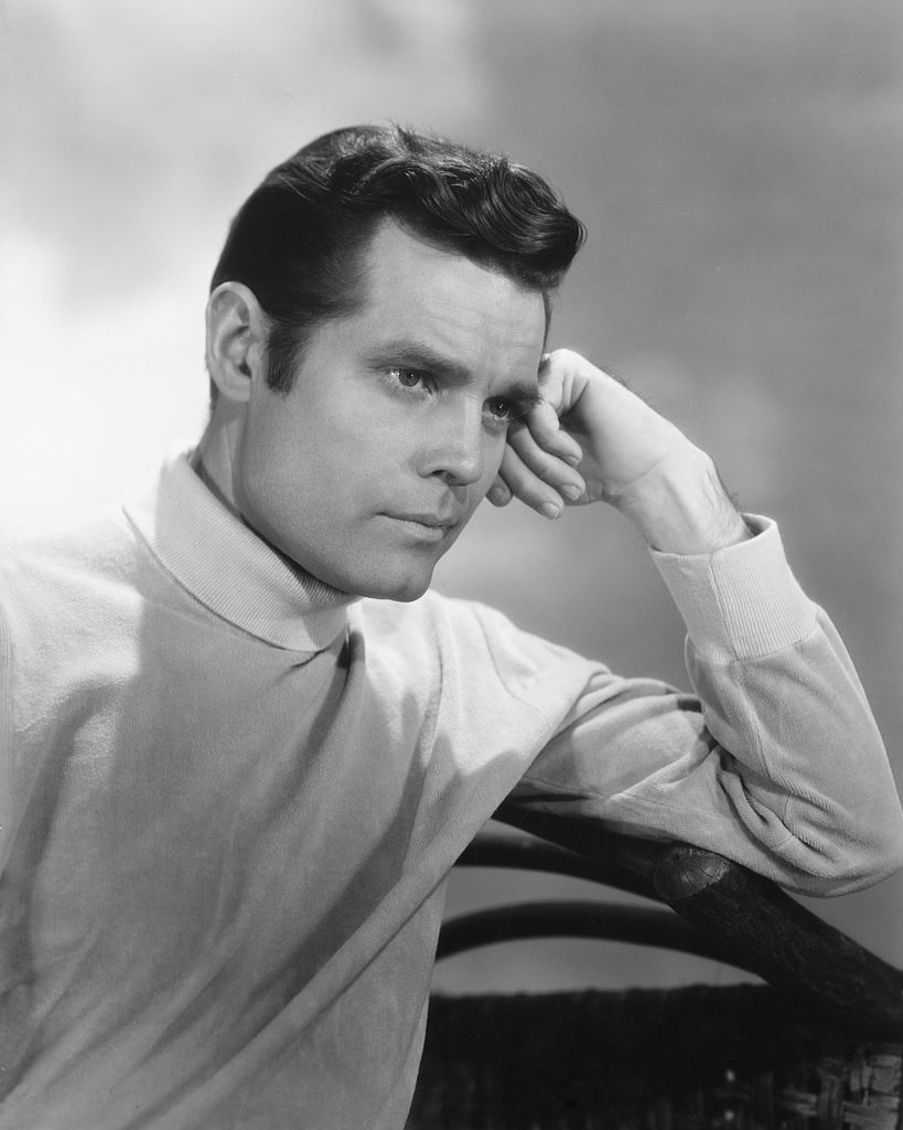 US actor Jack Lord wearing a white polo neck jumper and posing with his head resting against his hand, in a studio portrait, circa 1950. | Photo: Getty Images