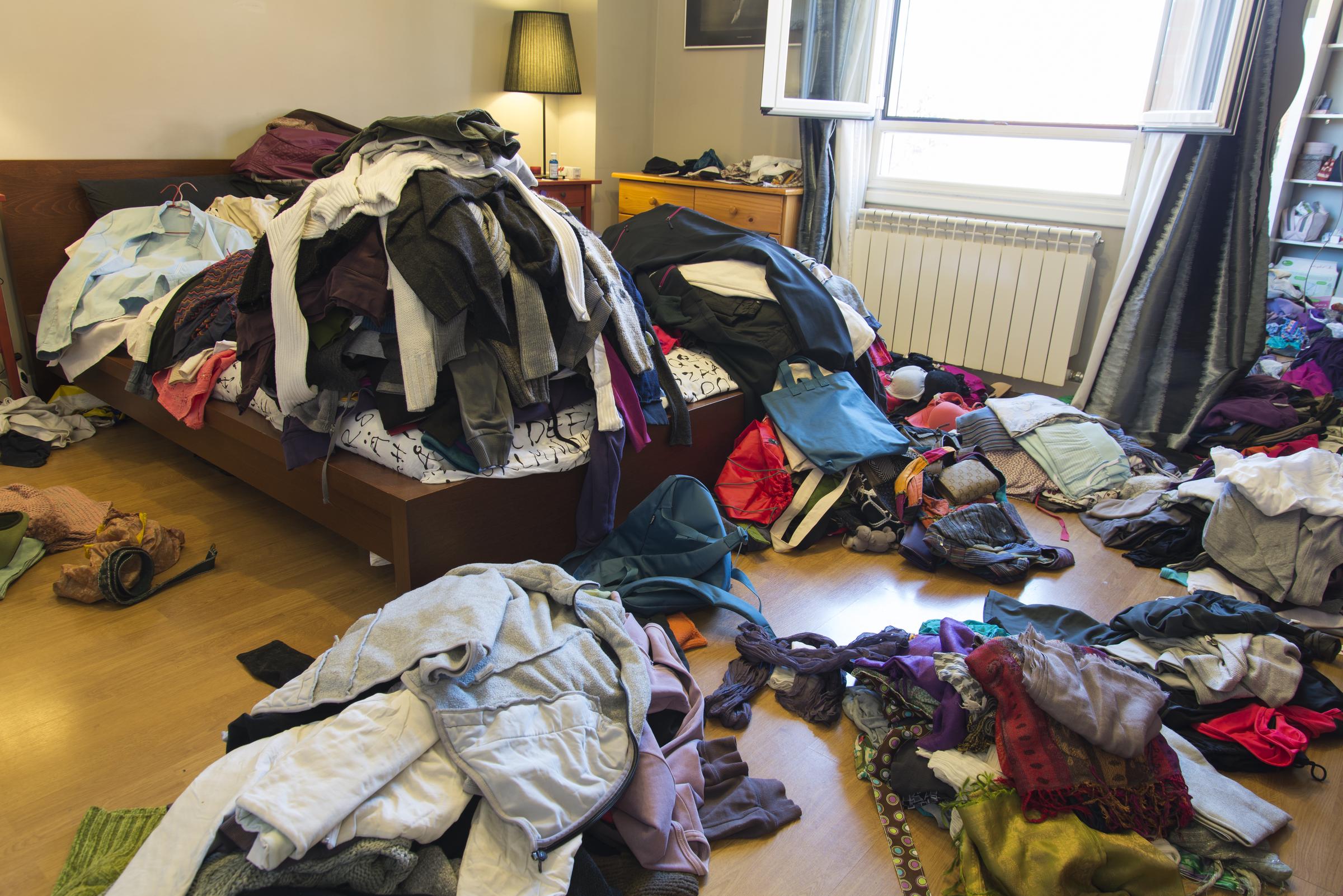 A bedroom scattered with piles of clothes | Source: Getty Images