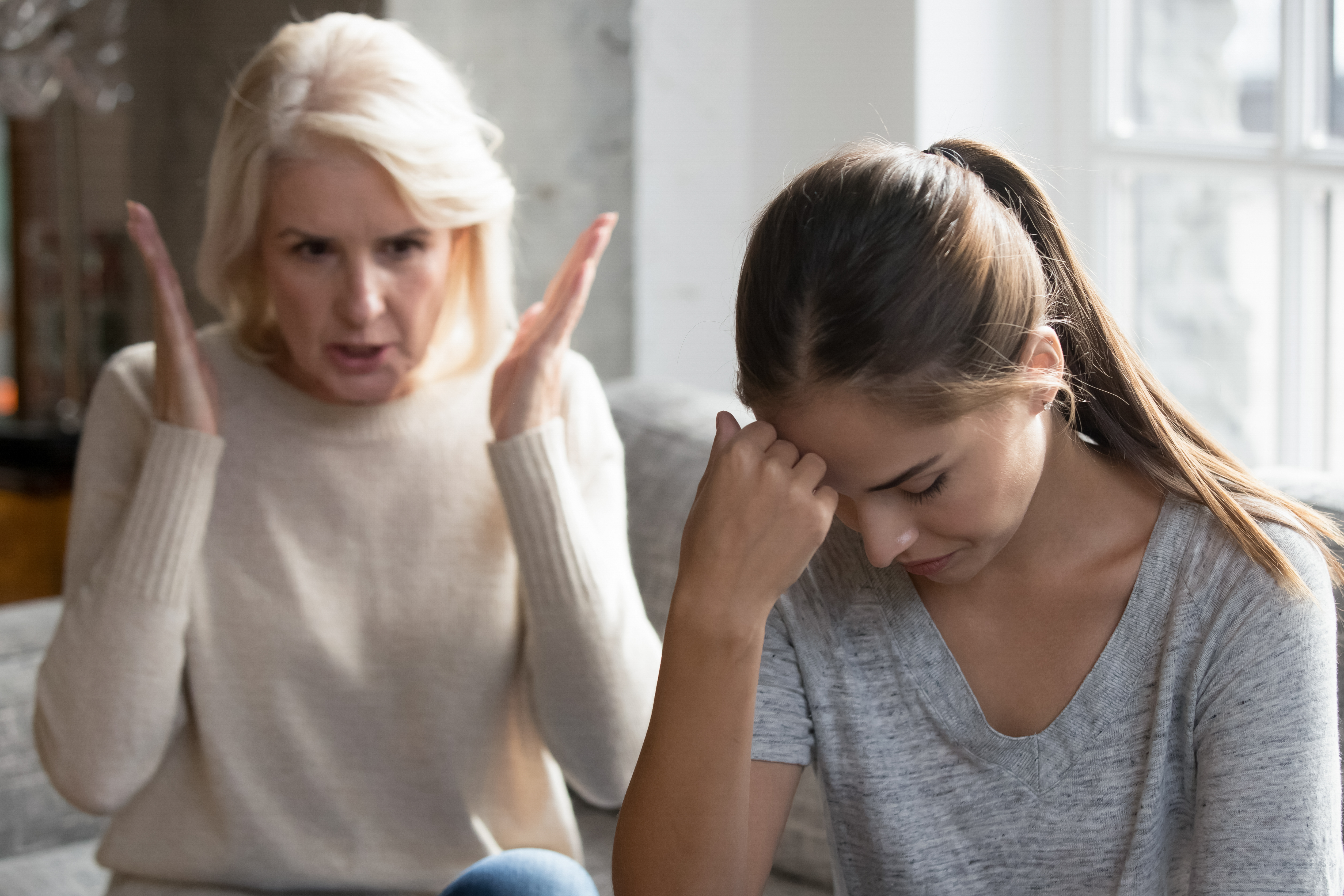 Mother-in-law sit on couch scolds daughter-in-law. | Source: Shutterstock
