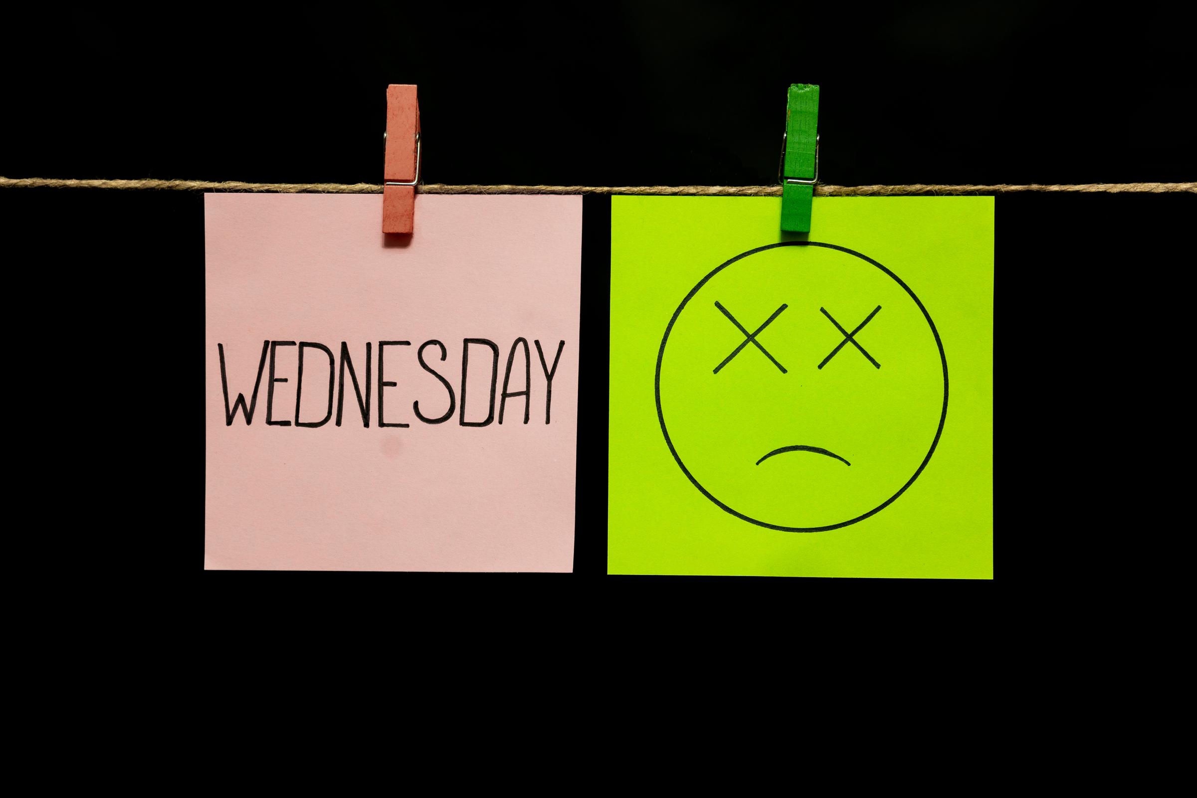 A pink piece of paper bearing the word Wednesday and a neon green piece of paper with a drawing of a sad face | Source: Shutterstock