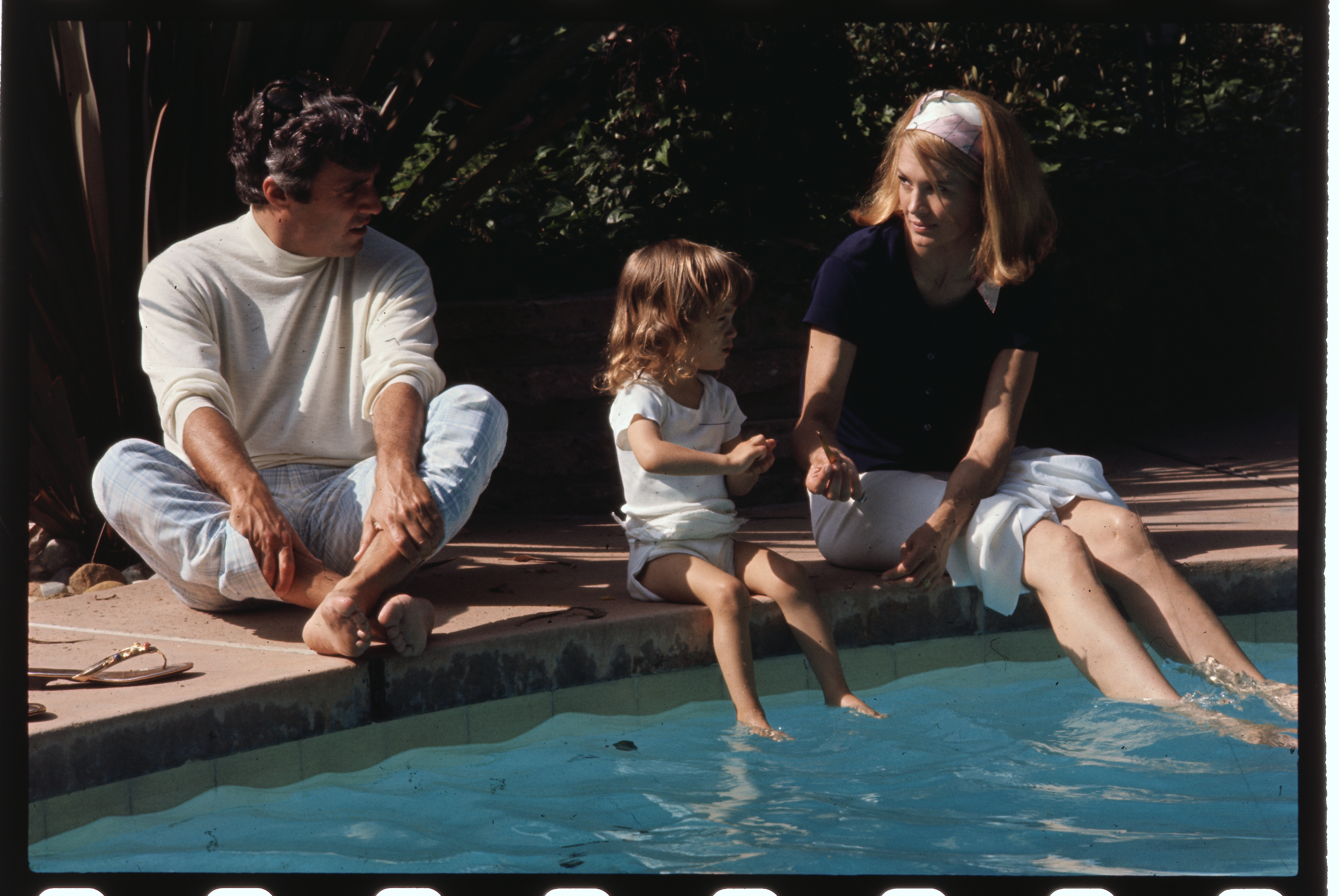 Burt Bacharach, his wife Angie Dickinson, and their 2-year-old daughter Nikki by the swimming pool of their Hollywood home on June 3, 1969 | Source: Getty Images