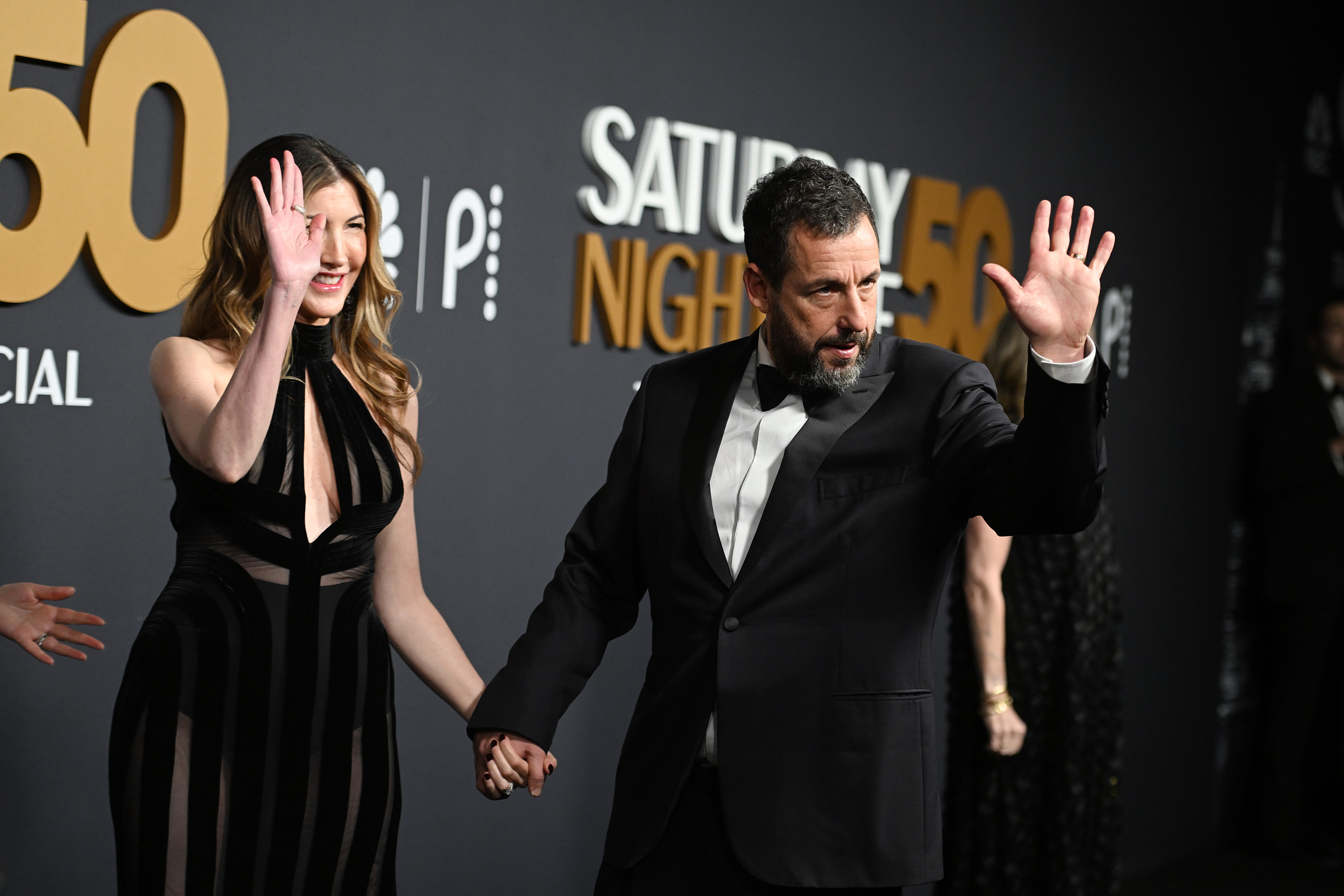 Jackie Sandler and Adam Sandler are seen waving at the cameras during their appearance at the "SNL50: The Anniversary Special" at 30 Rockefeller Plaza on February 16, 2025, in New York | Source: Getty Images