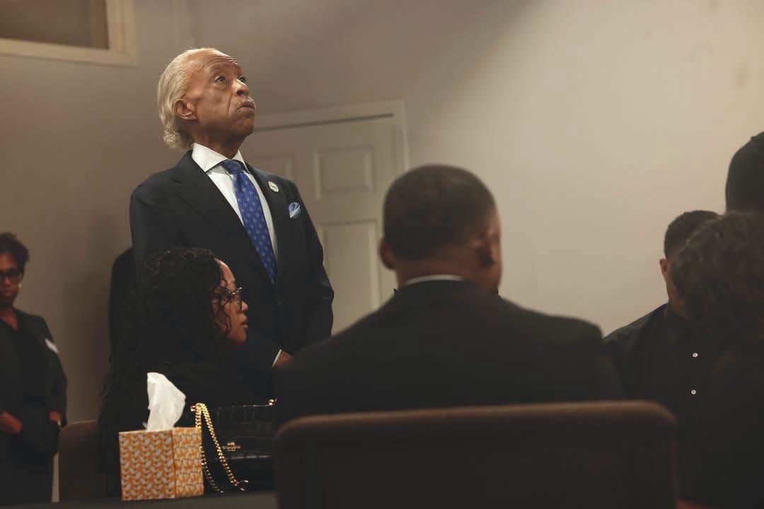 Rev. Al Sharpton stands in quiet reflection while Christine Wonsley sits solemnly beside a box of tissues in the gathering room. | Source: Facebok/realsharpton