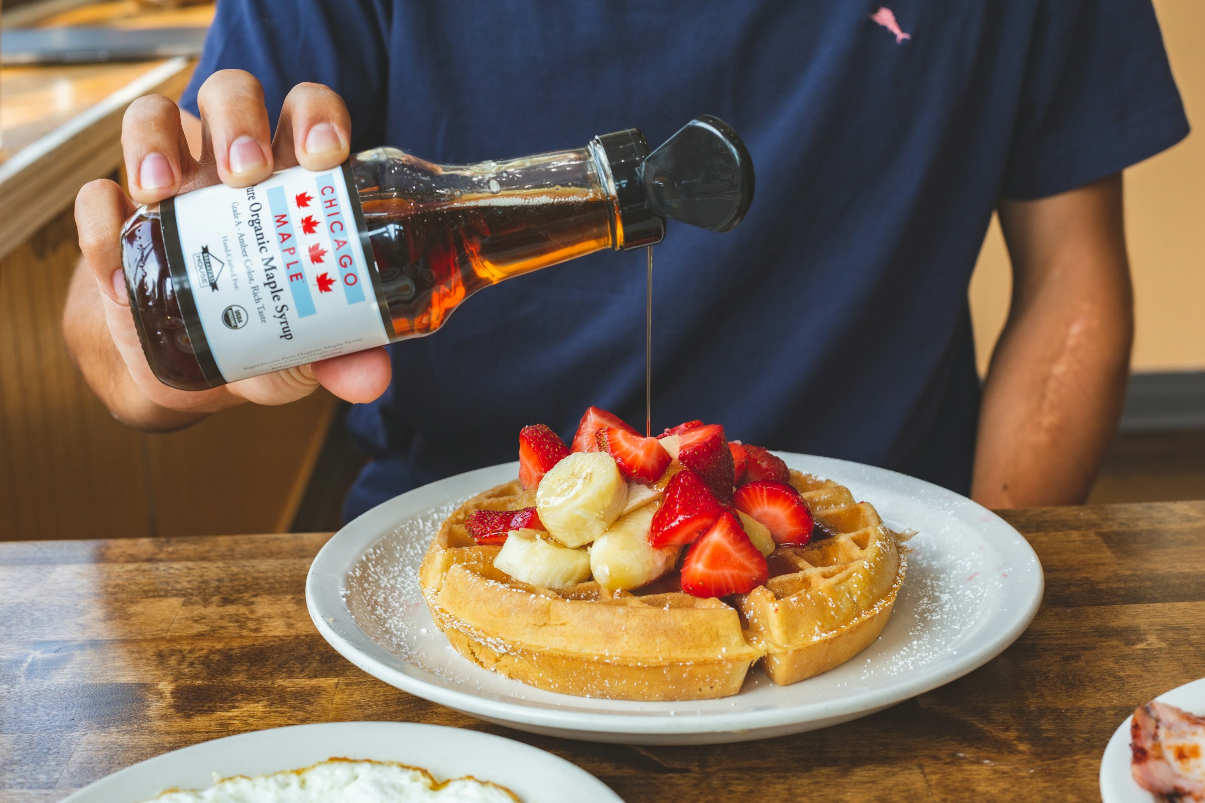 A person pouring syrup on waffles | Source: Unsplash