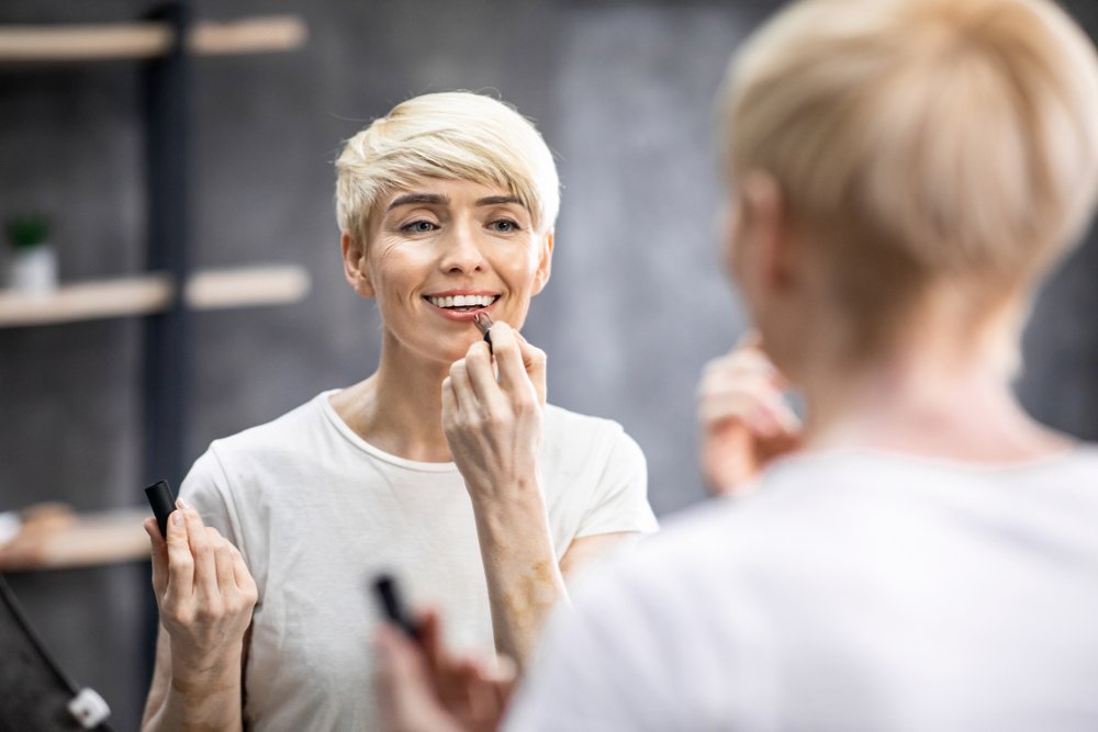 Mujer pintándose los labios en el espejo. | Foto: Shutterstock