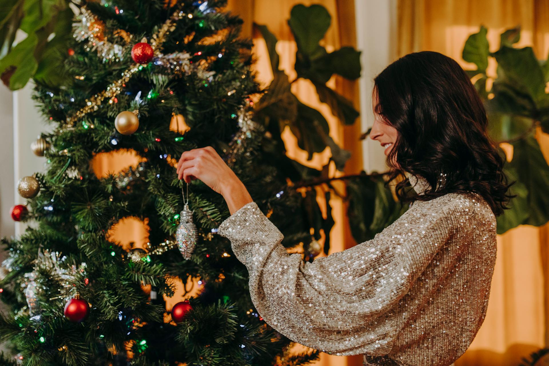 A cheerful woman decorating a Christmas tree | Source: Pexels