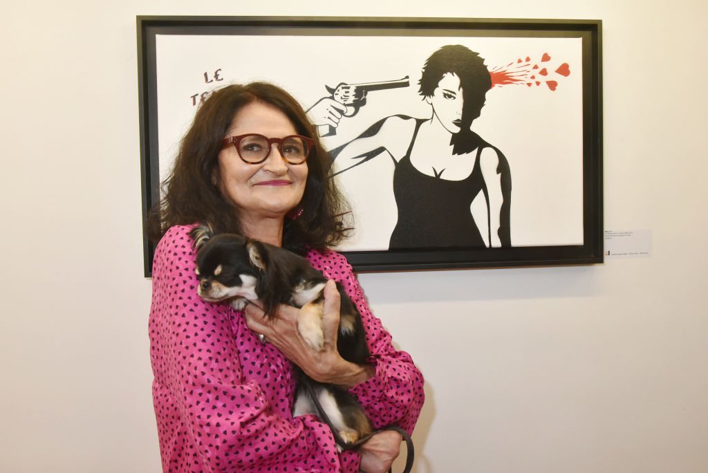 Street graffiti artist/illustrator Miss Tic (Miss.Tic or Radhia de Ruite) and her dog Nana posing with her work during the exhibition 