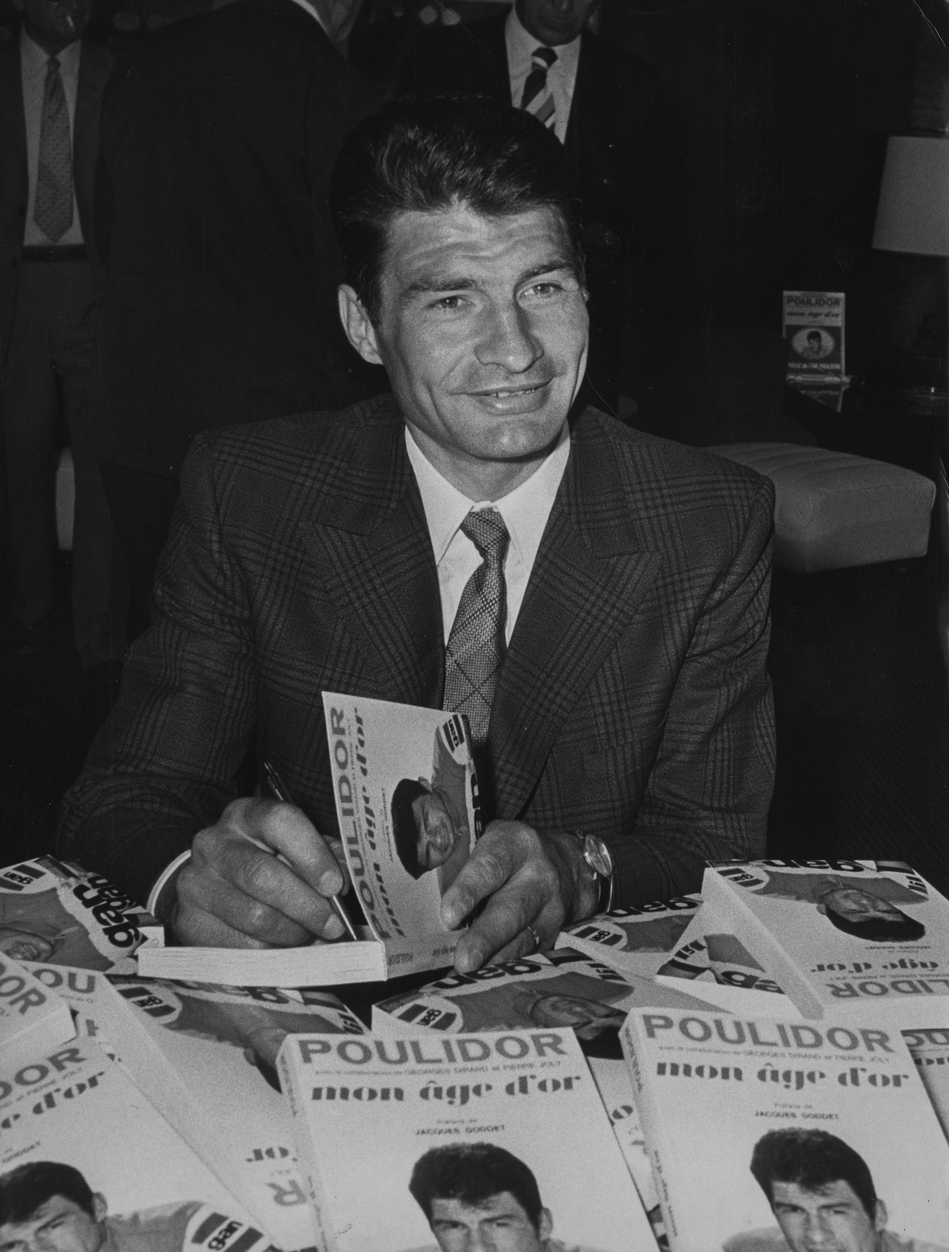 Raymond Poulidor, a photographié des exemplaires dédicacés de son livre'Mon Age D'Or', lors d'une réception à Paris, vers 1972. | Photo : Getty Images