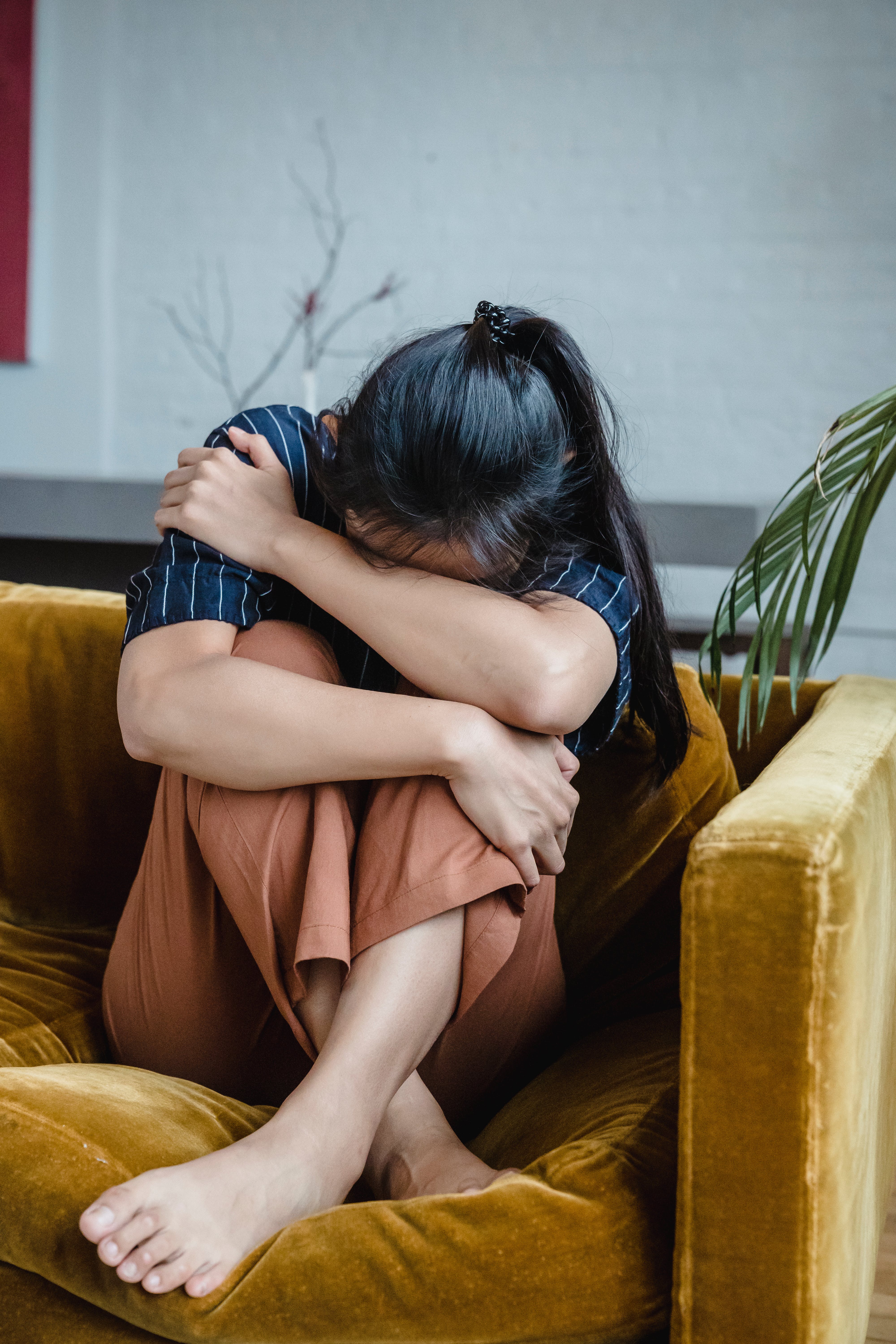 A woman curled up while crying on the couch | Source: Pexels