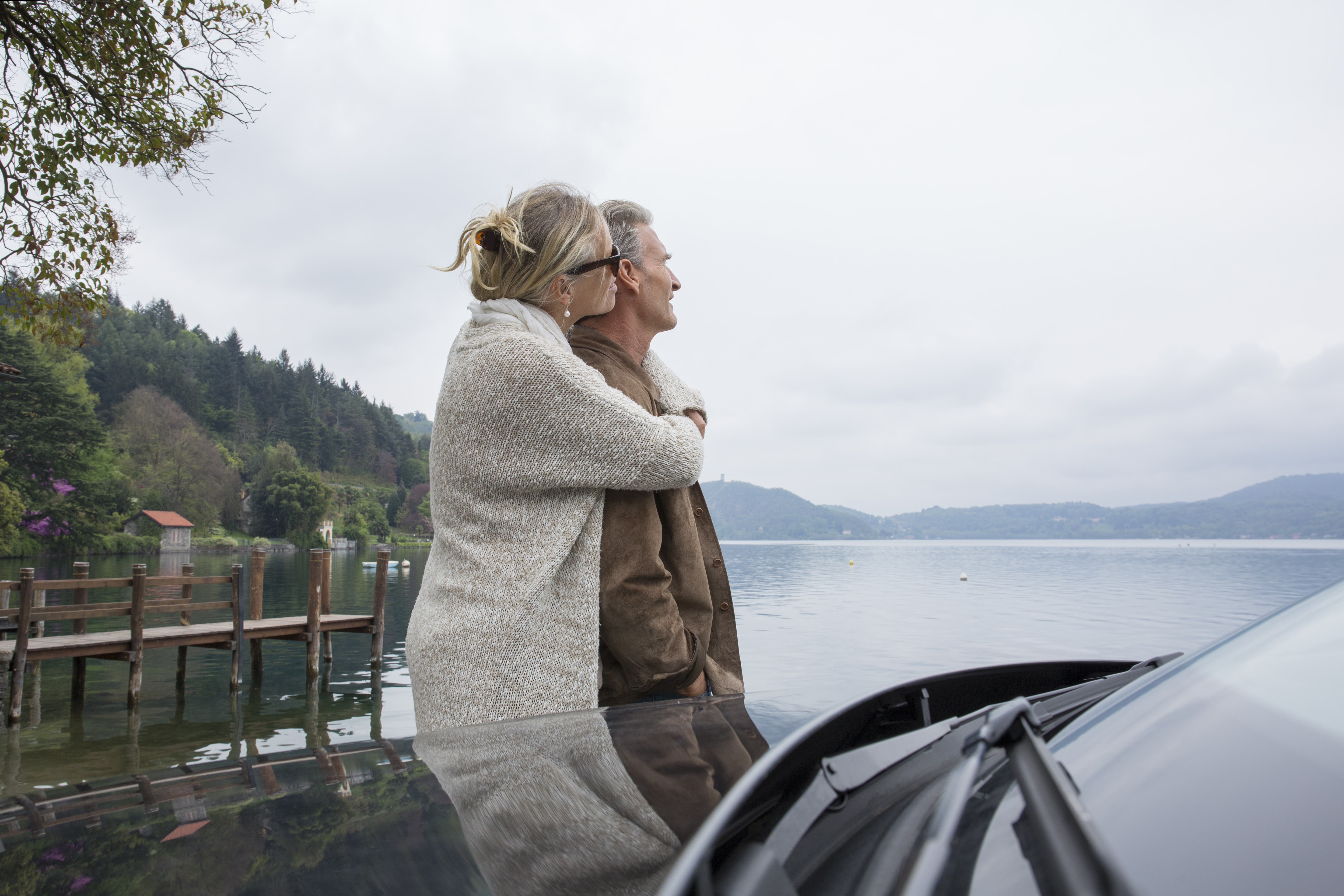 Couple embracing standing beside their car near a lake | Source: Getty Images