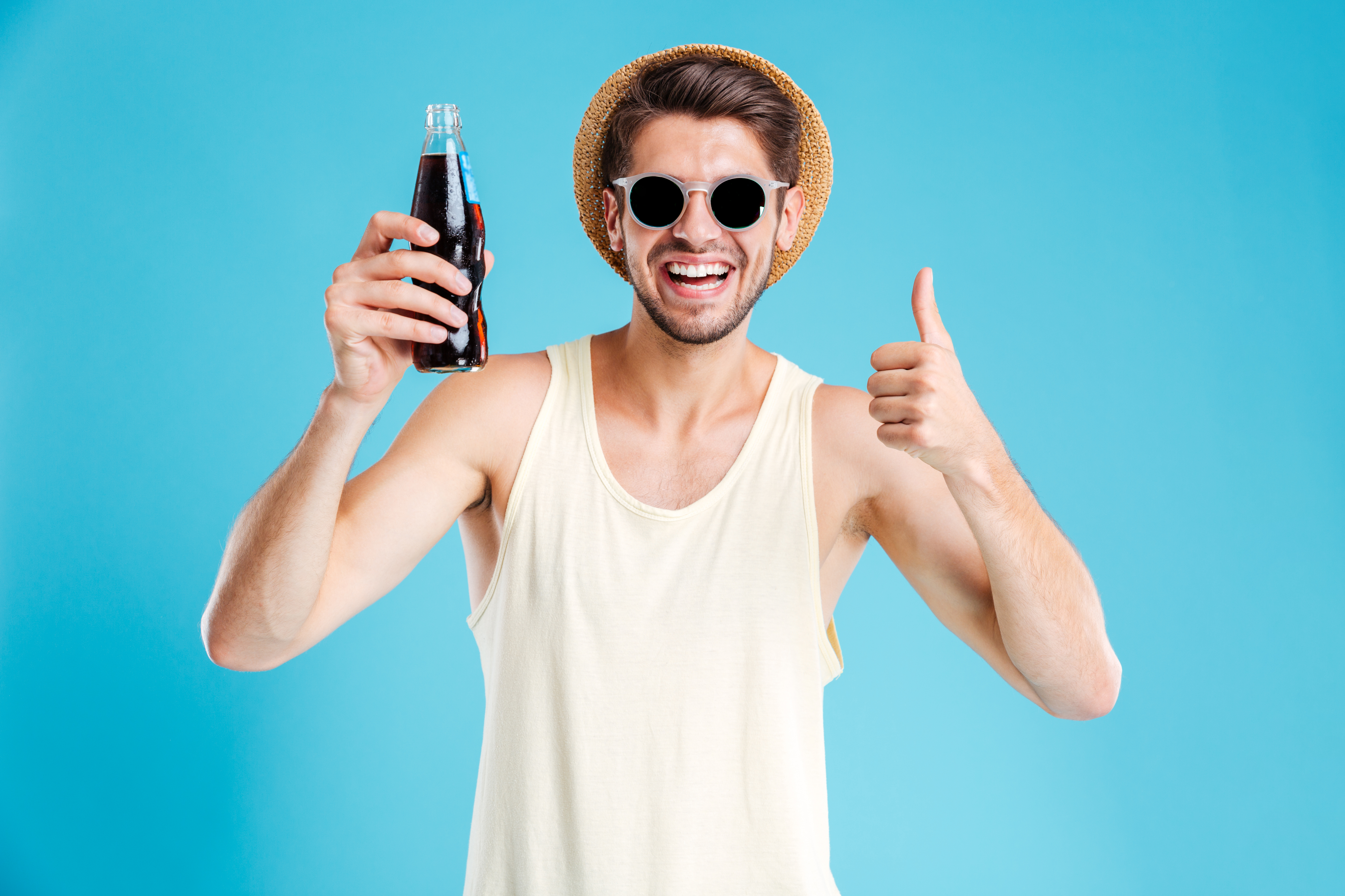 A happy young man holding a soda | Source: Shutterstock