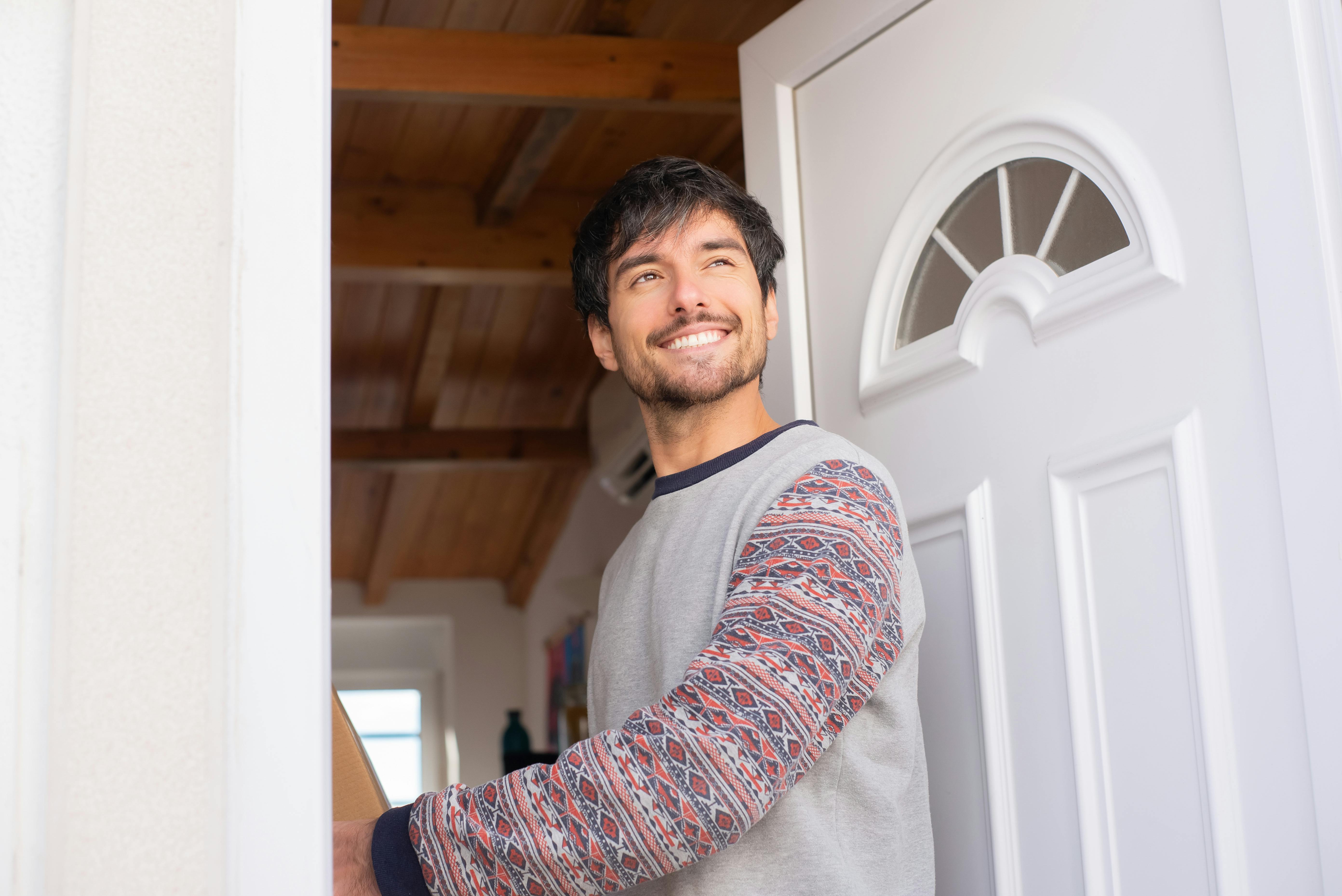 A man smiling while standing at the doorway | Source: Pexels