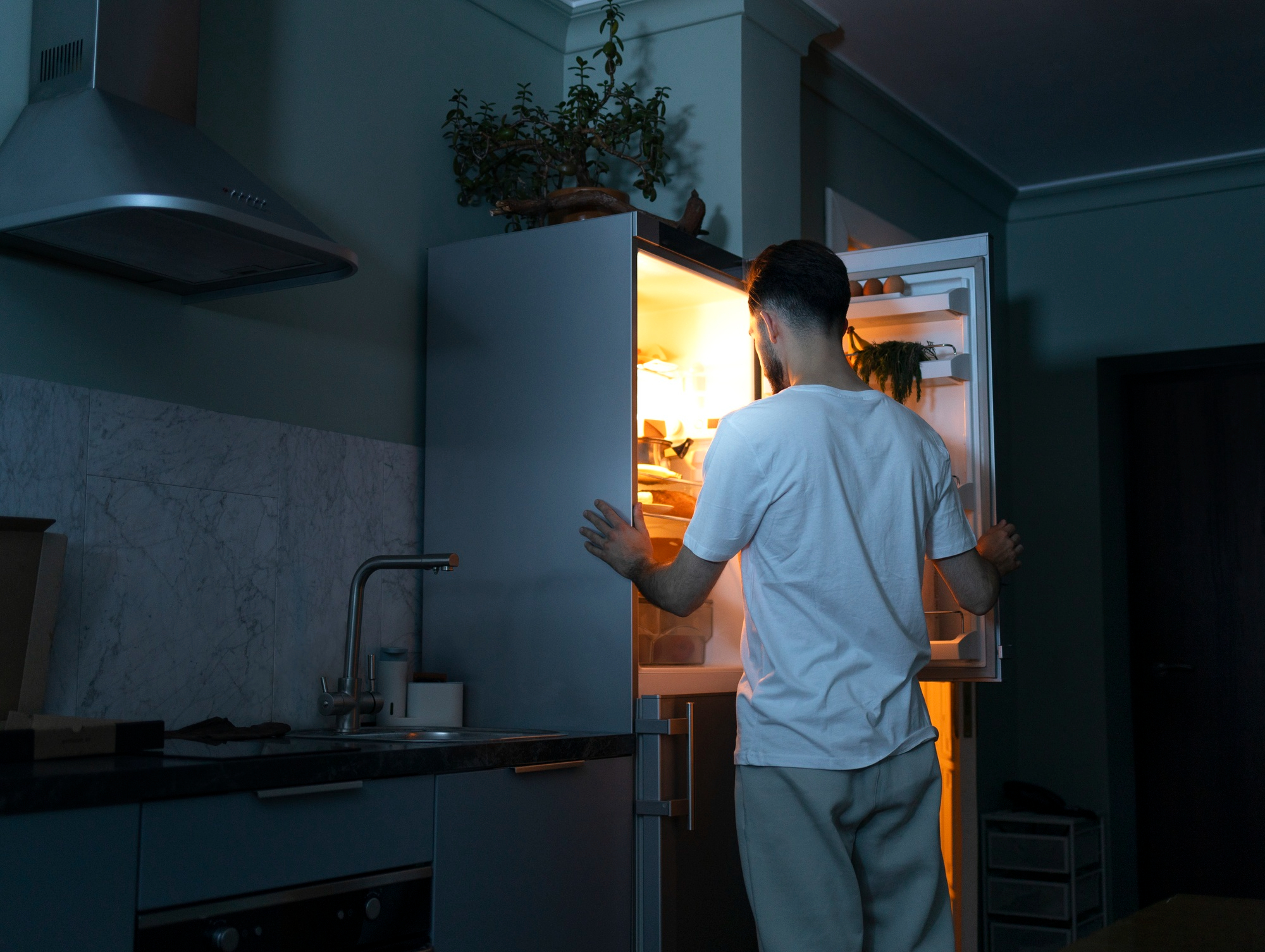A man looking for snacks in the fridge | Source: Freepik