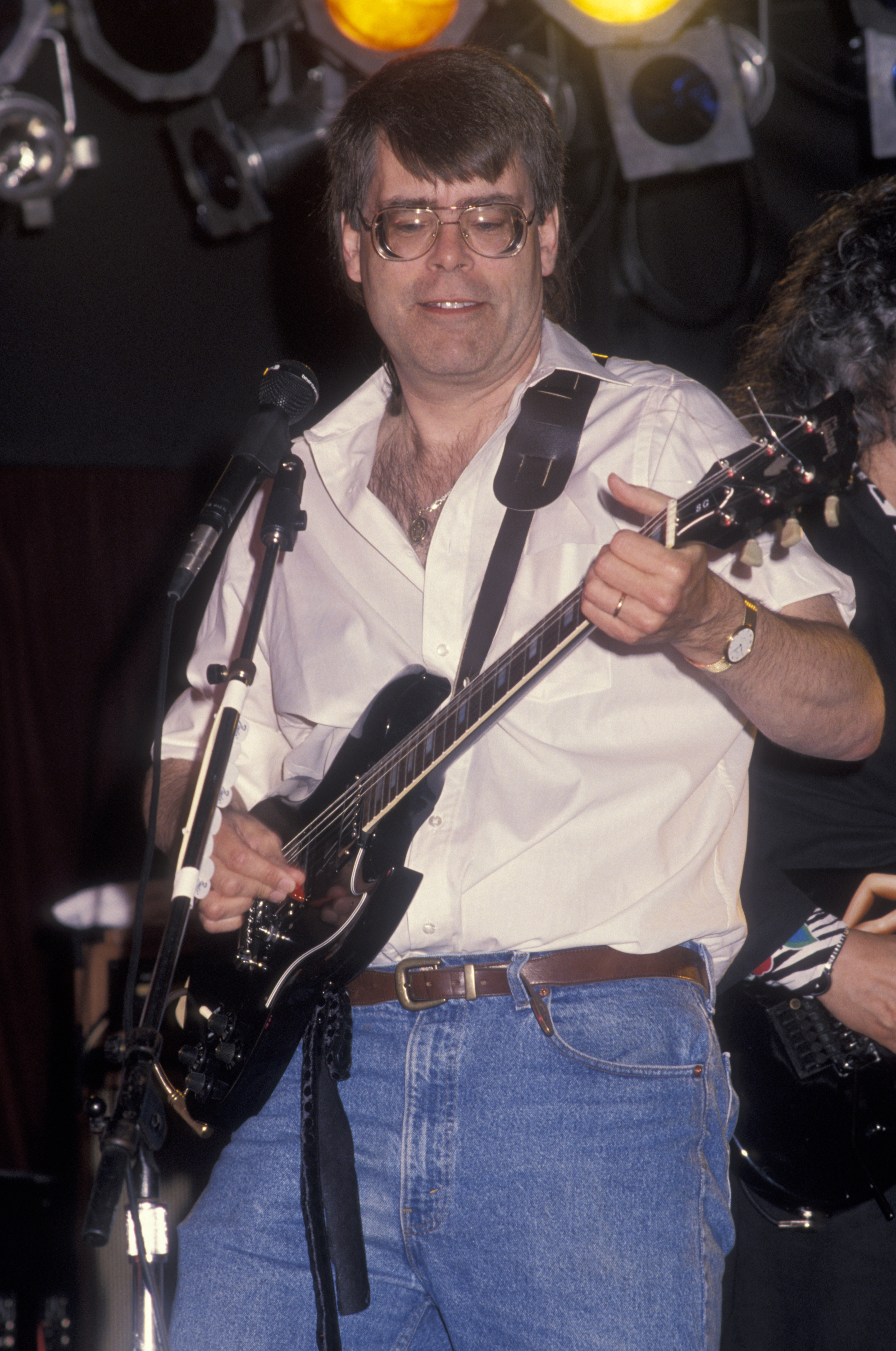 Clad in a crisp white shirt and blue jeans, author Stephen King strums a black guitar during a Rock Bottom Remainders performance at the Cowboy Boogie Club in Anaheim.