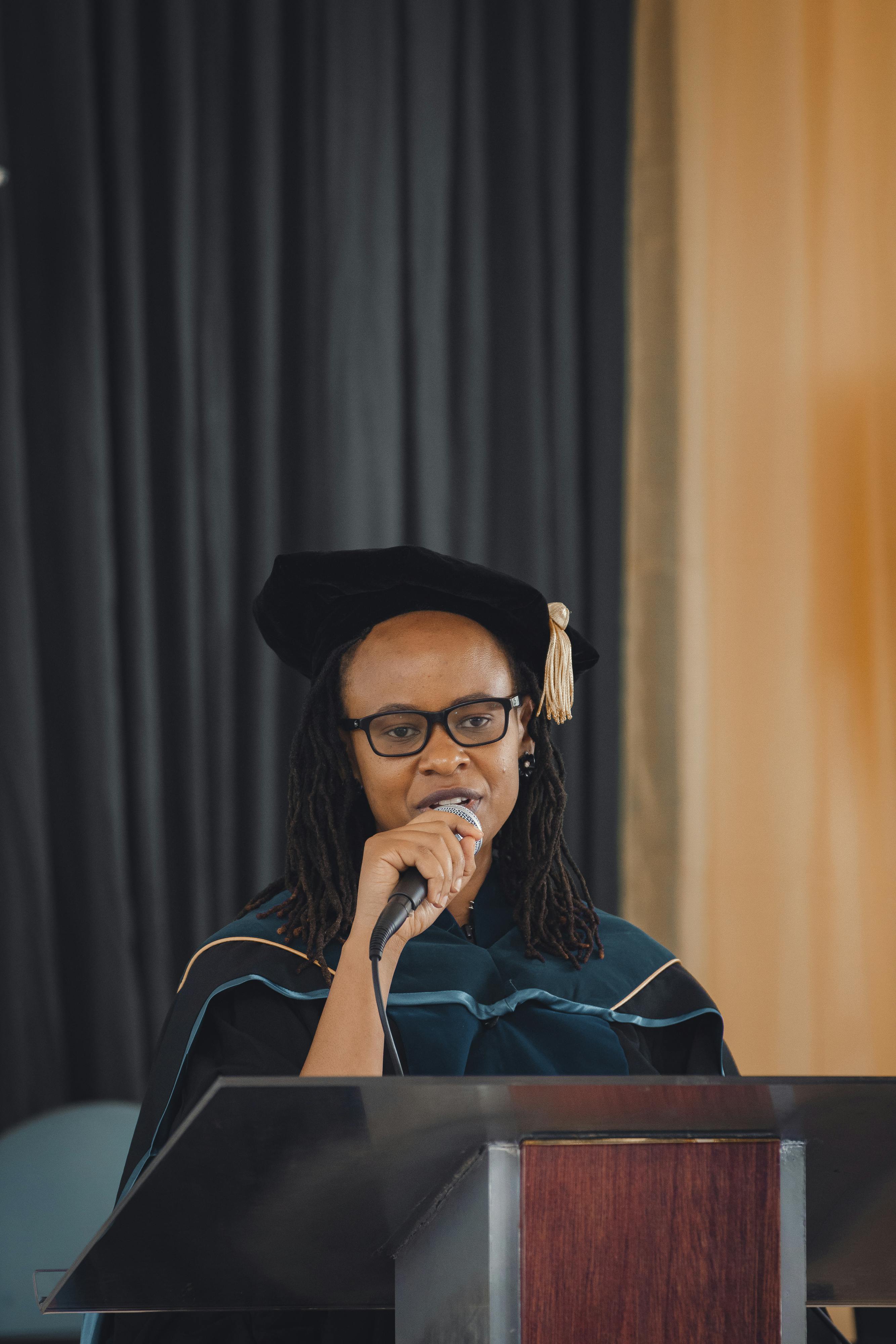 A college graduate speaking on a microphone on stage | Source: Pexels