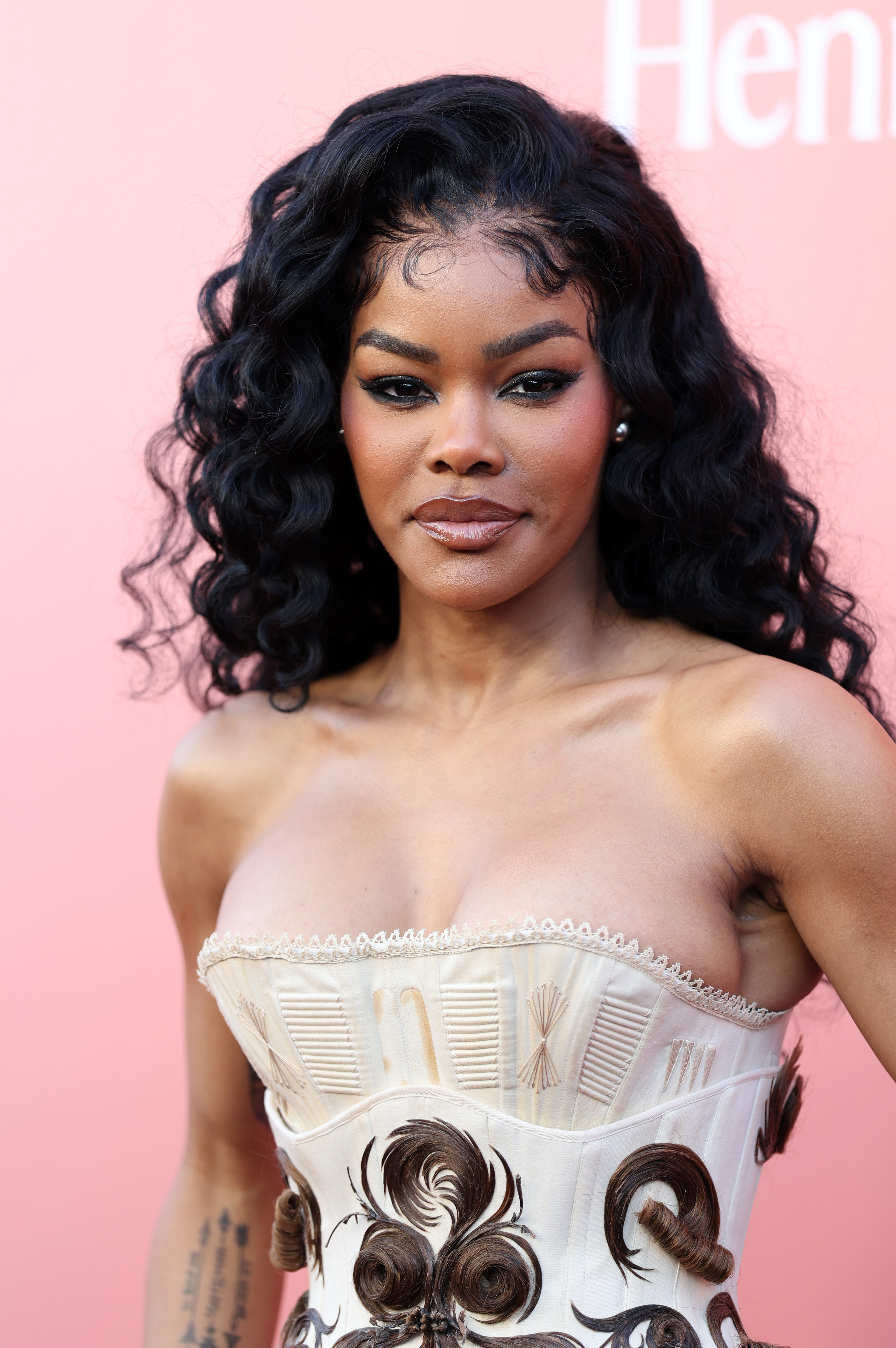 Teyana Taylor faces forward, highlighting the intricate corset design with swirling details and a polished glam look during her red carpet appearance.