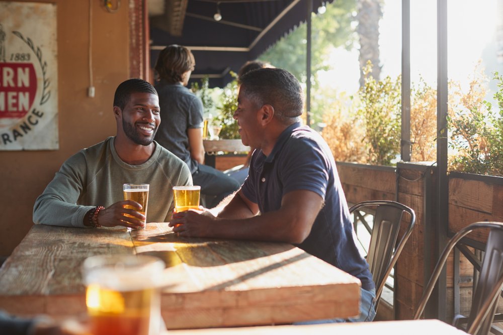 Two men drinking beer at a bar. | Photo: Shutterstock