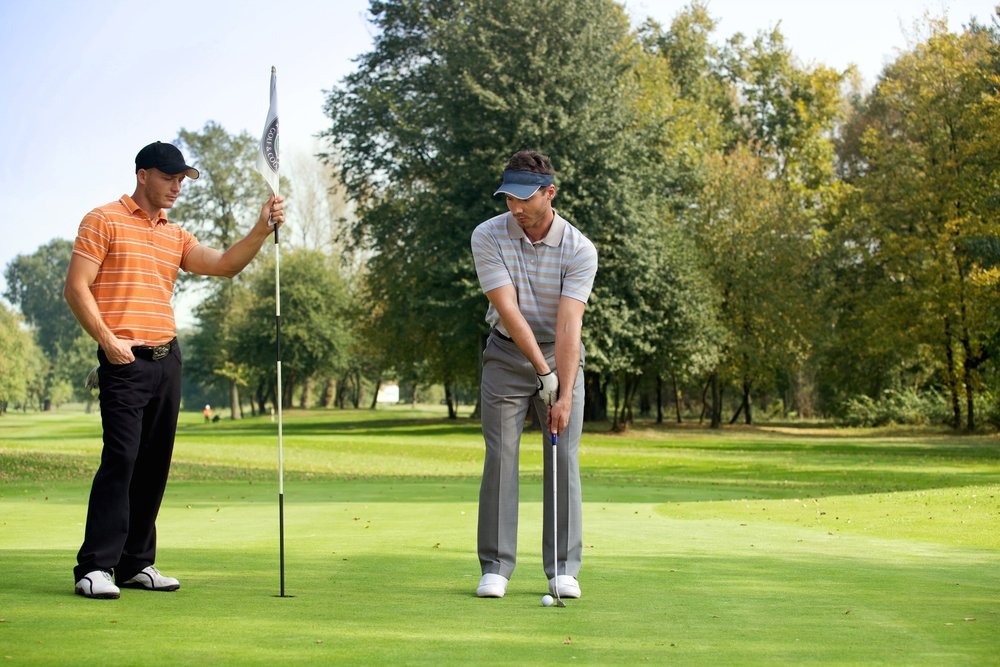 Two young men playing golf in golf course. | Photo: Shutterstock