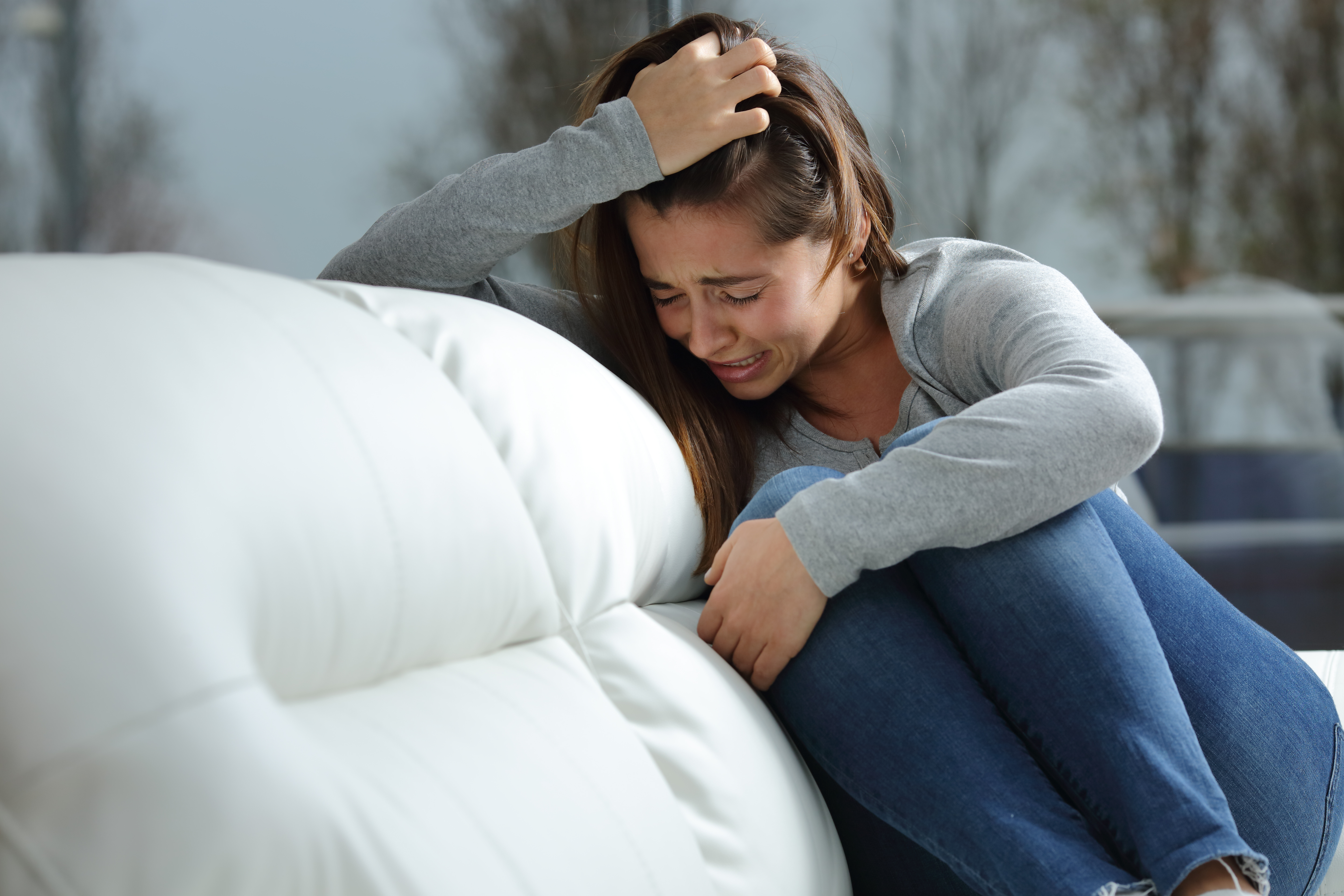 A girl crying on a couch | Source: Shutterstock