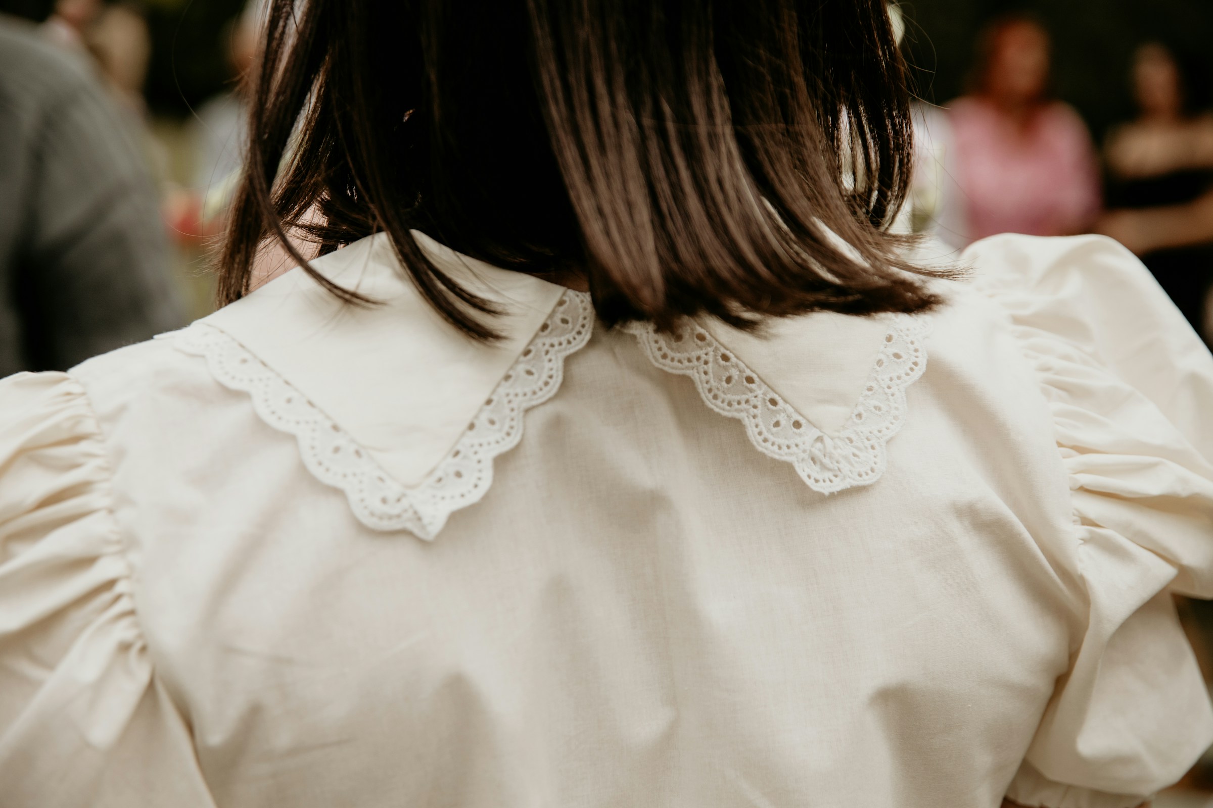 A back view shot of a woman wearing a white blouse with a scalloped collar | Source: Unsplash