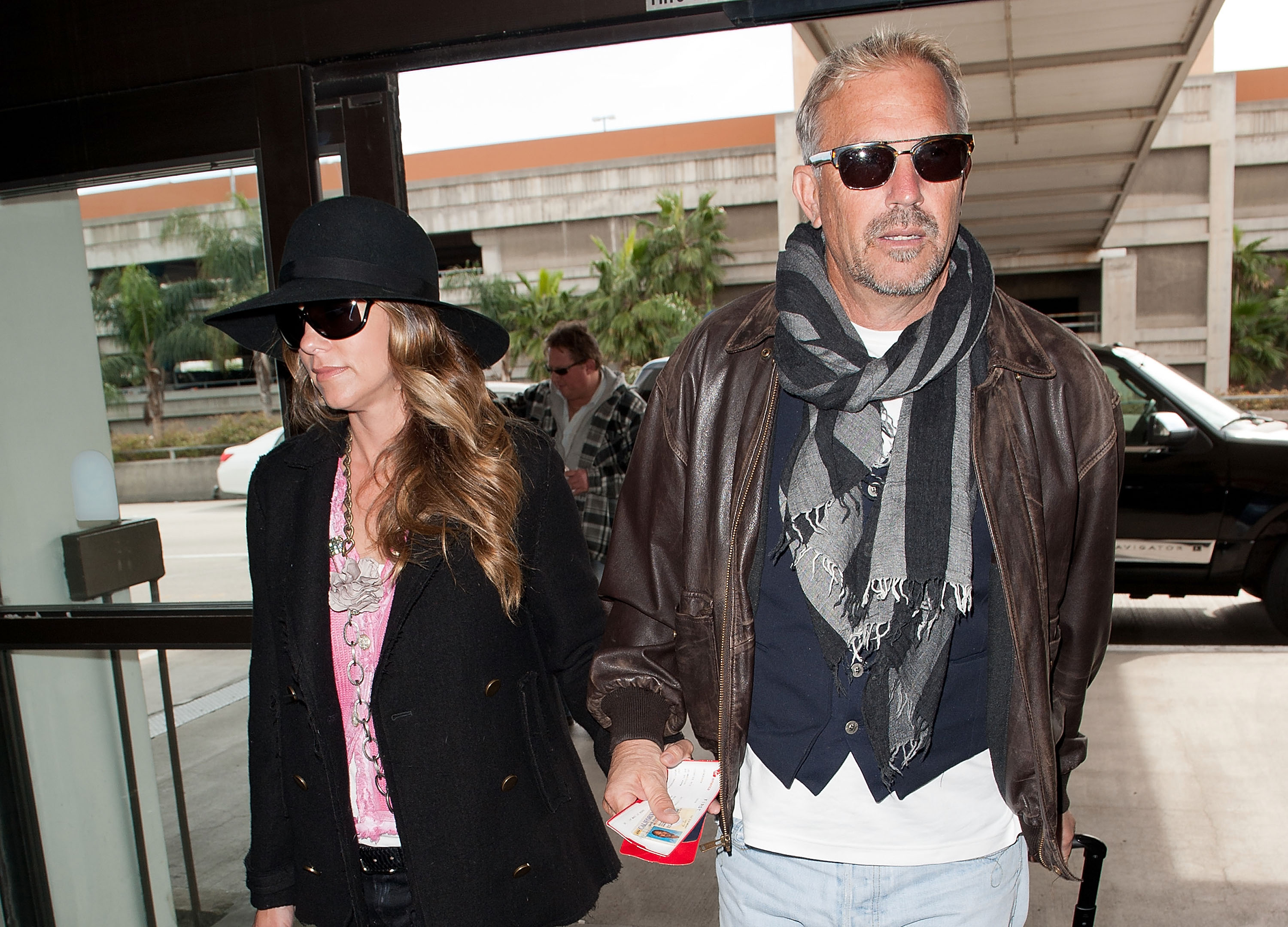 Kevin Costner and Christine Baumgartner were spotted in travel mode at LAX, both sporting dark sunglasses and effortlessly cool looks. With Baumgartner in a wide-brimmed hat and the actor wrapped in a striped scarf, the couple kept a low profile while navigating the terminal hand in hand.