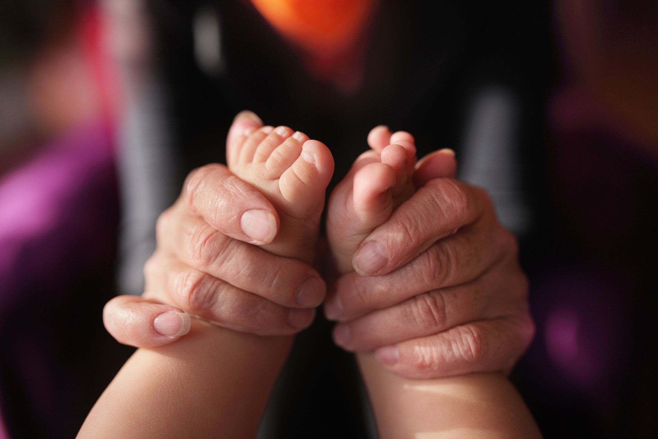 Mains d'une grand-mère tenant les pieds du bébé. | Photo : Getty Images