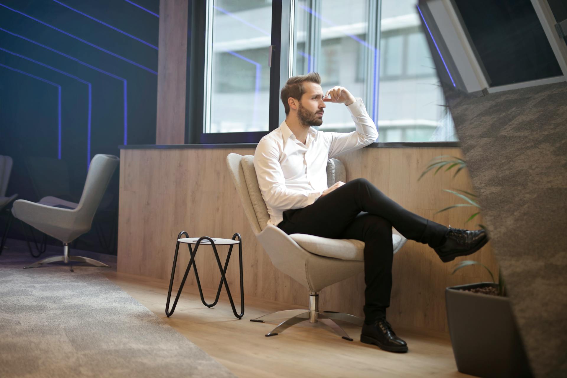 A thoughtful man sitting near the window in an office setting | Source: Pexels