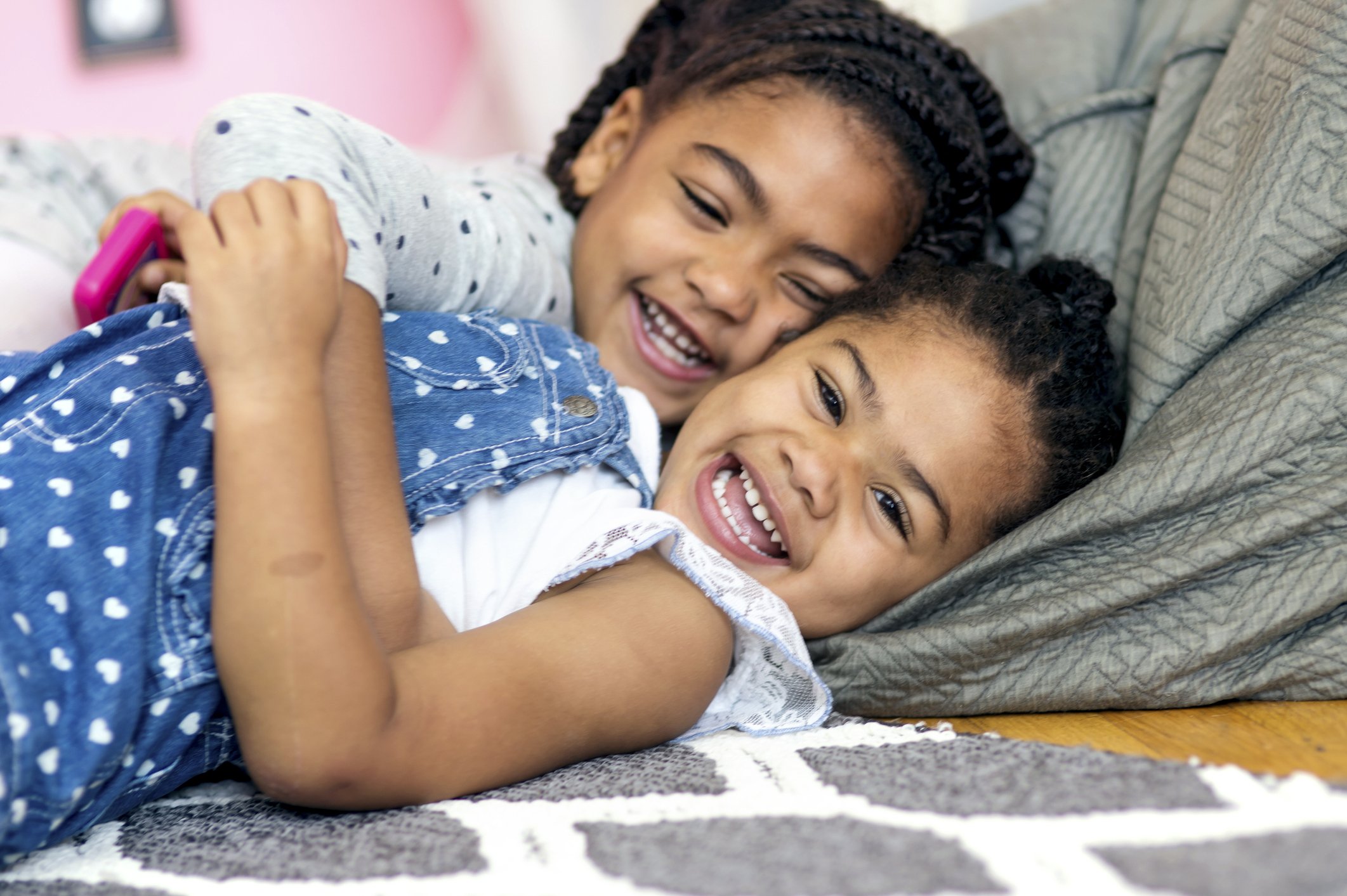 Cute African American girl tickling younger sister on the floor | Photo: Getty Images