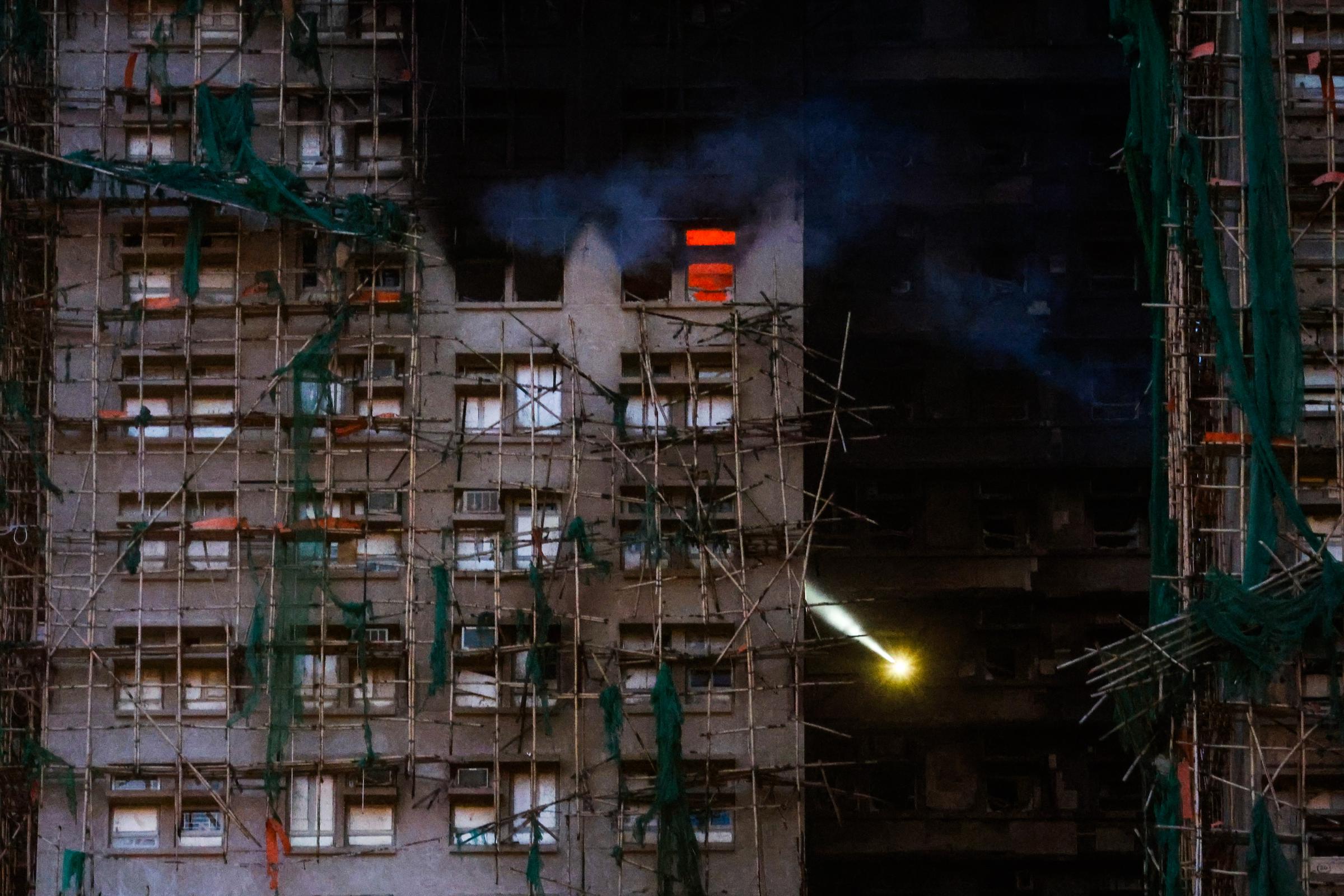 Rescuers with flashlights search for survivors at the Wang Fuk Court residential buildings, in Tai Po, Hong Kong, on November 27, 2025. | Source: Getty Images