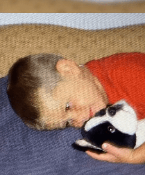 Un Logan Kavaluskis plus jeune allongé avec son chiot Boston Terrier en jouet.┃Source : instagram.com/insideedition