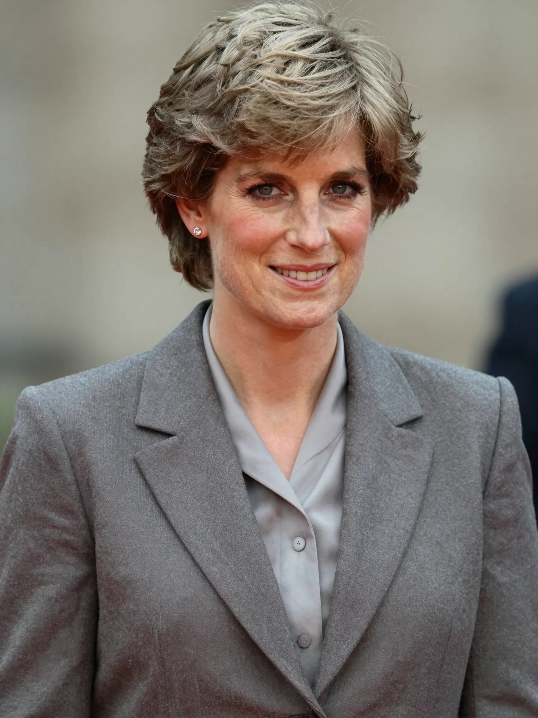 In this AI-generated image, Princess Diana is imagined as a woman of 64, her familiar features softened by time but still instantly recognisable. Dressed in a structured grey blazer and blouse, she appears composed and dignified — a vision of the modern royal she may have become, had history allowed. | Source: Grok