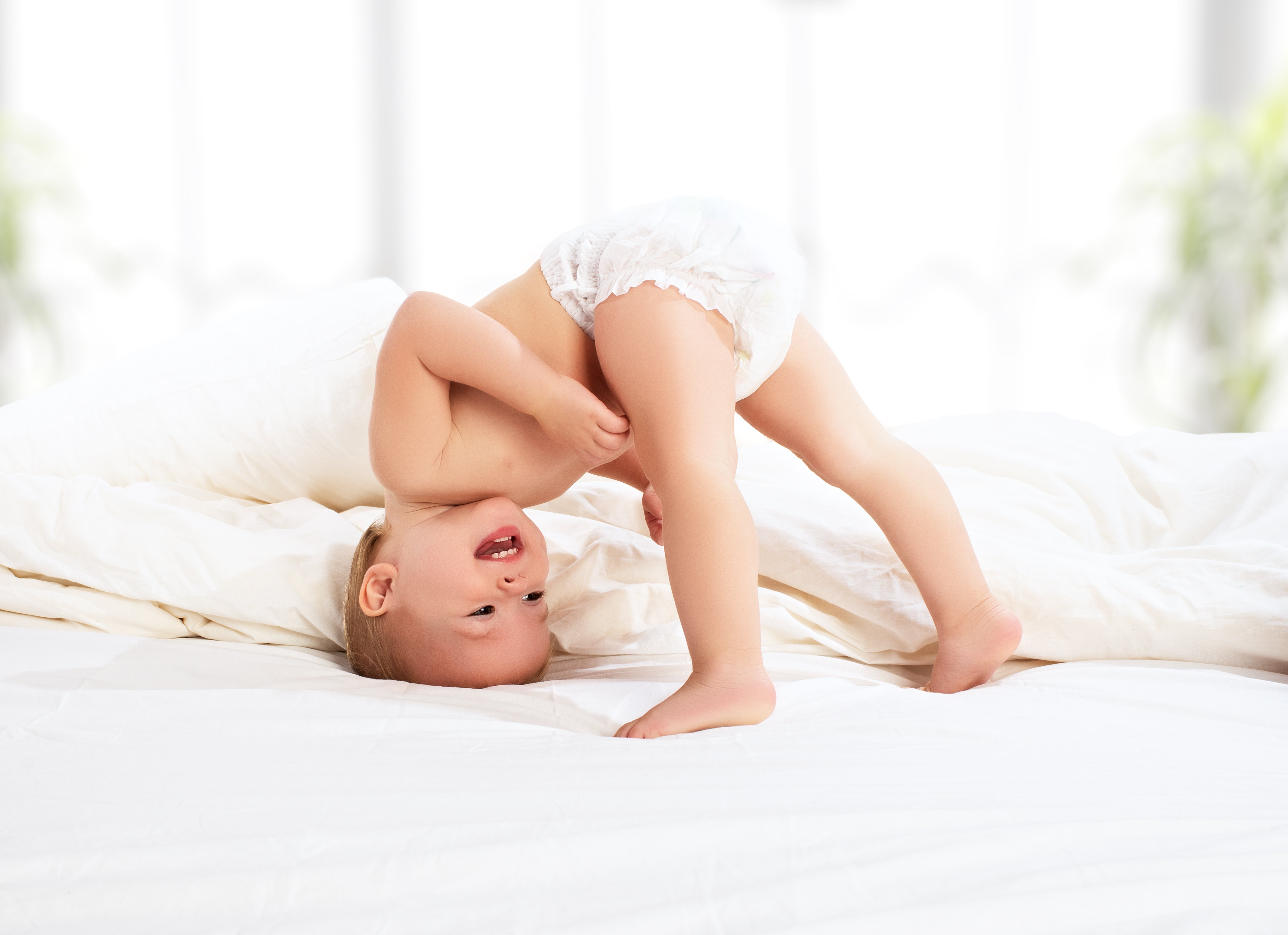 Un bébé jouant au lit | Photo : Shutterstock