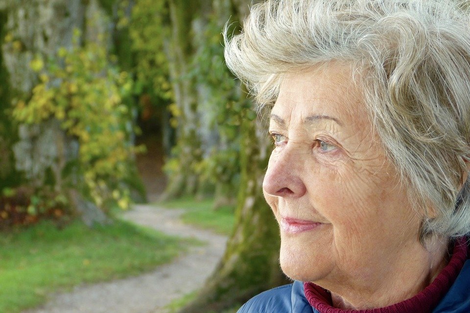 Anciana sonríe complacida mientras su mirada se pierde en el horizonte. | Foto: Pixabay