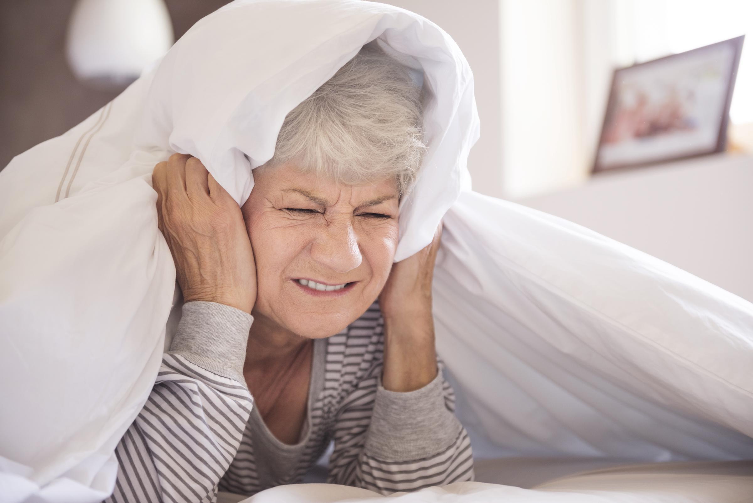 An elderly woman covering her ears | Source: Freepik