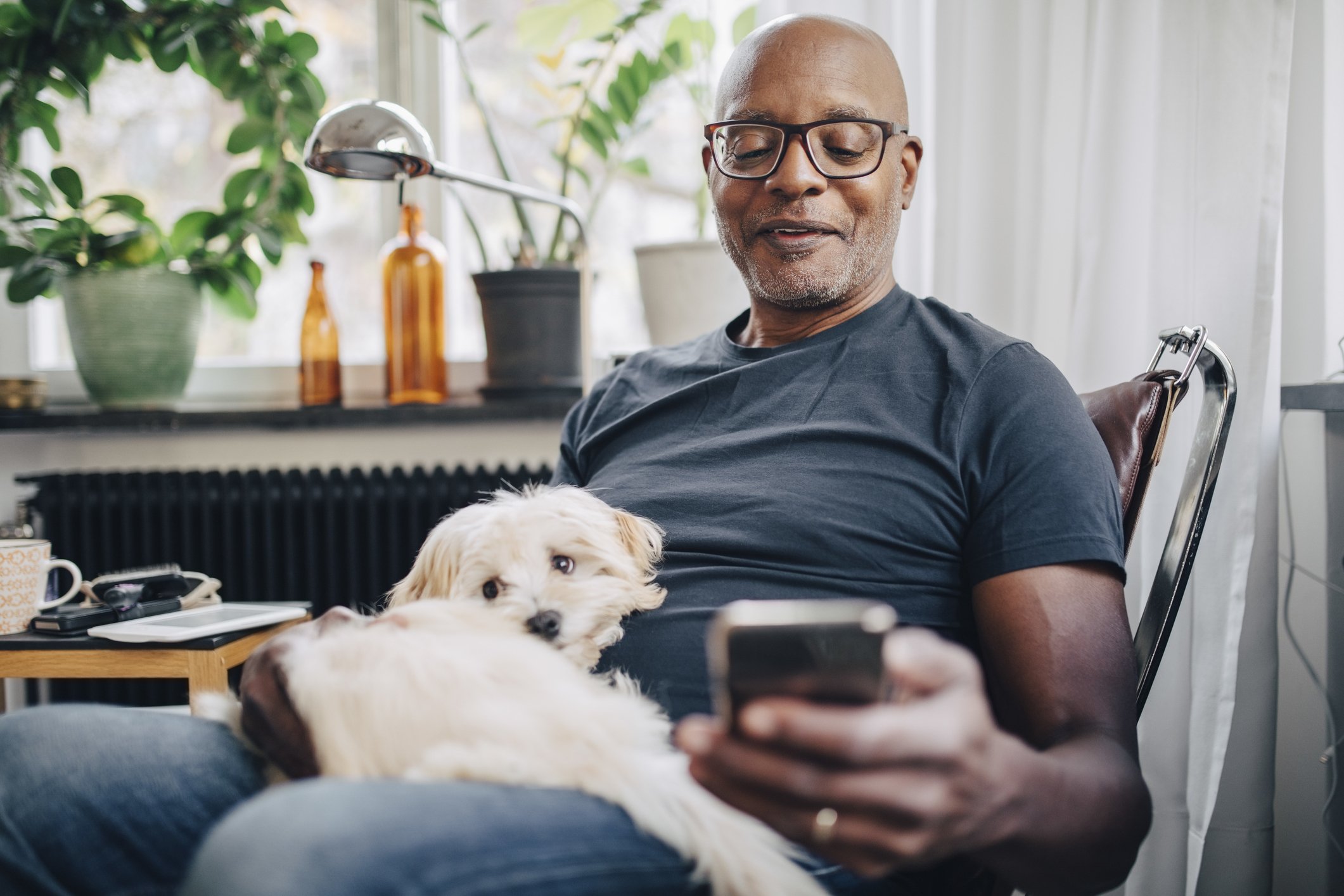 A photo of a man smiling and holding his dog and his phone. | Photo: Getty Images