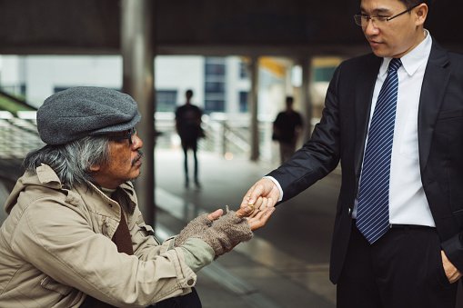 Photo of a business man giving money to a homeless man | Photo: Getty Images
