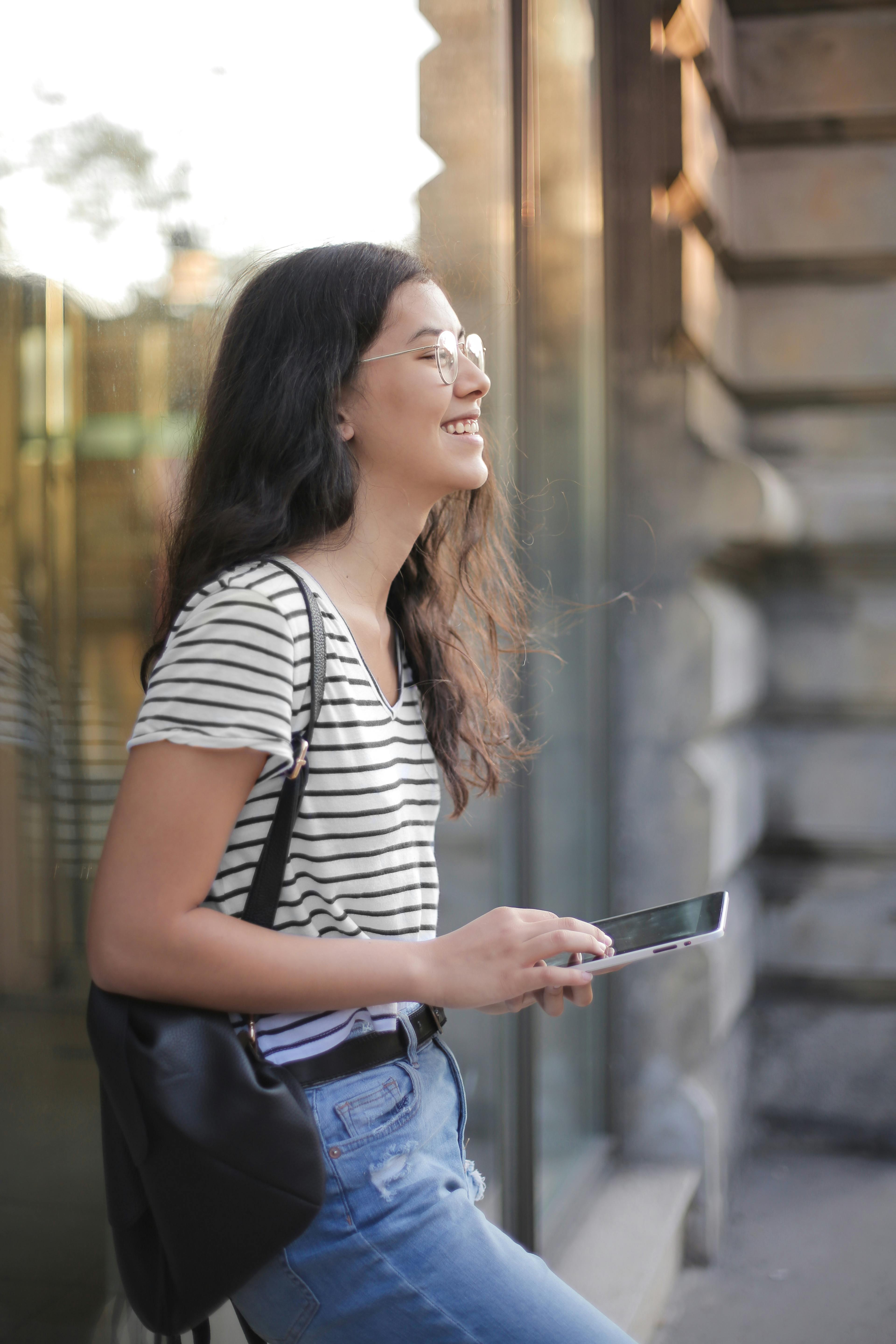 A woman smiling while holding her phone | Source: Pexels