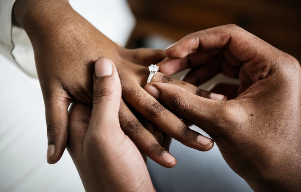 A newly engaged man putting the ring on his fiancee's finger. | Source: Shutterstock