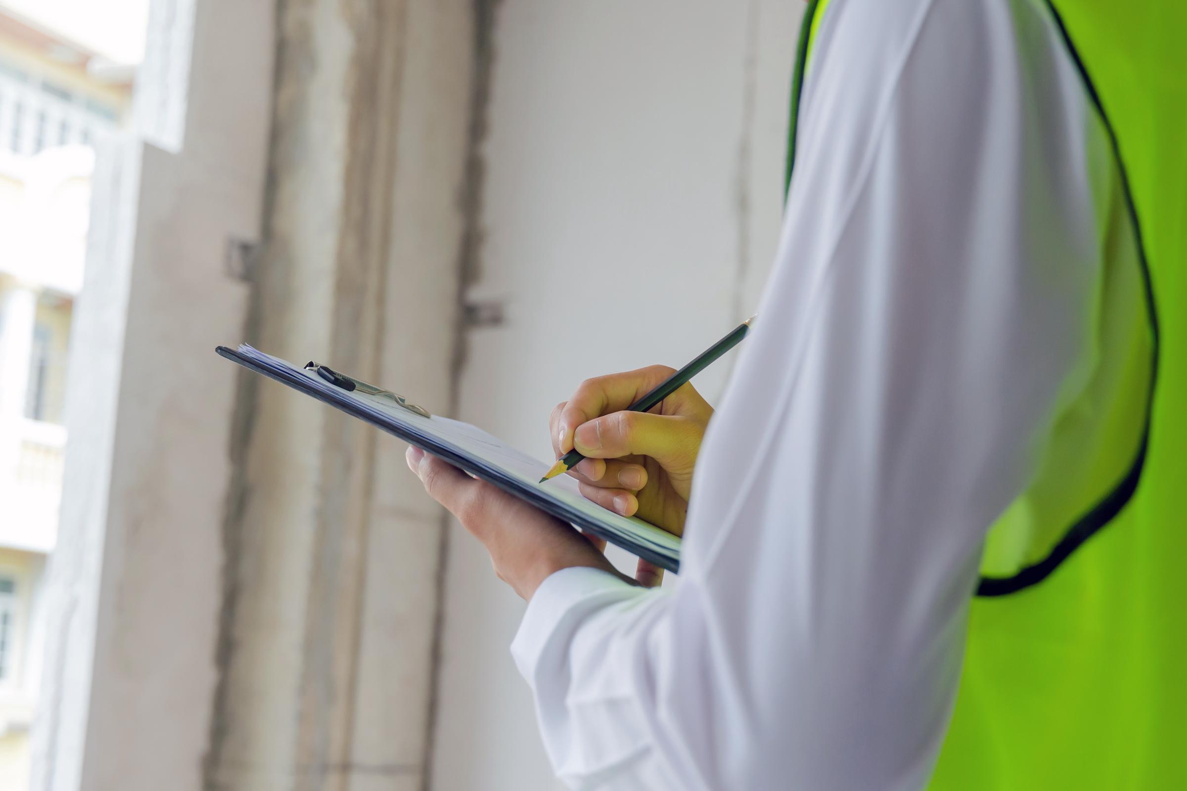 A person wearing a reflector jacket writing on a clipboard | Source: Shutterstock