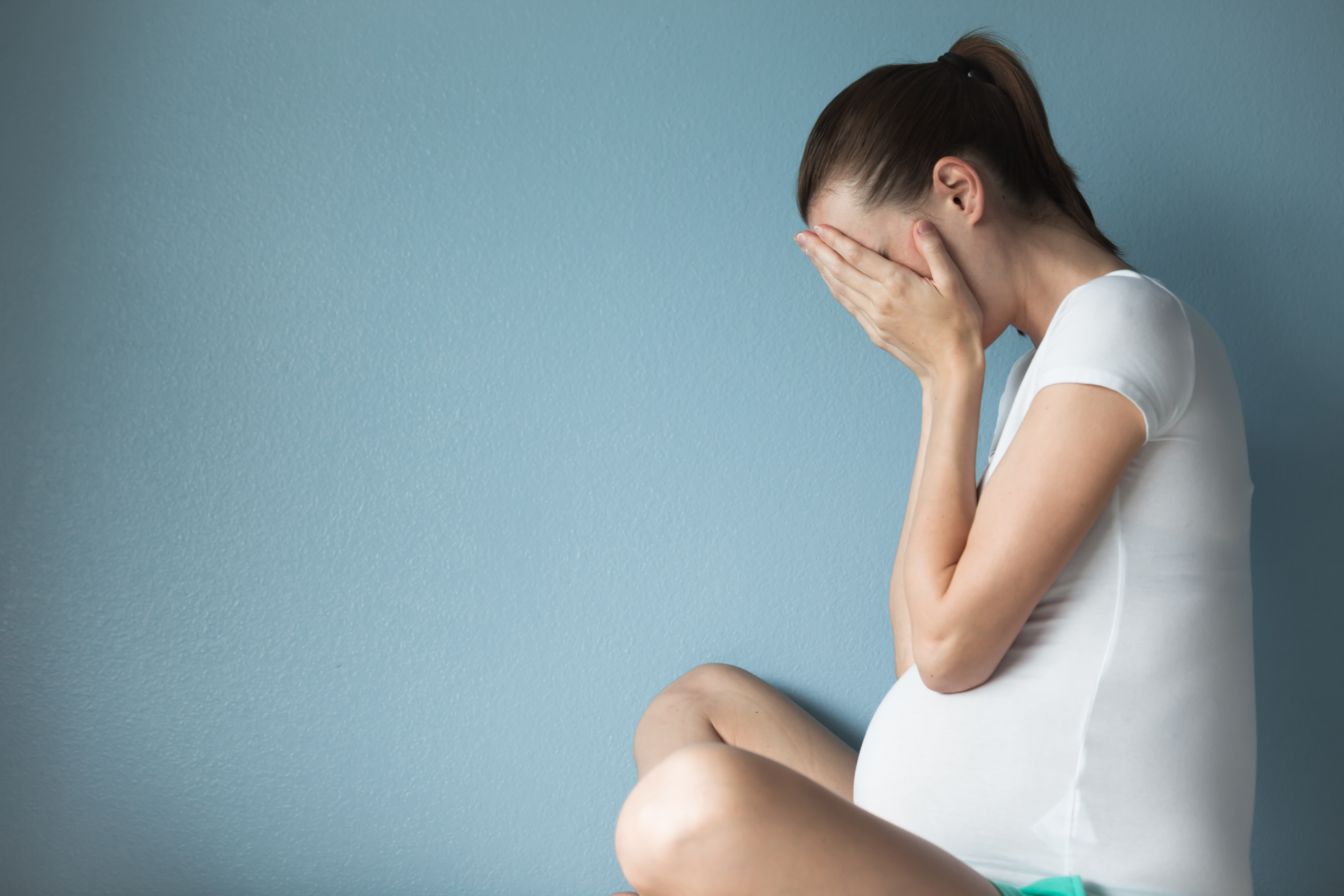 An upset pregnant woman holding her belly | Source: Shutterstock