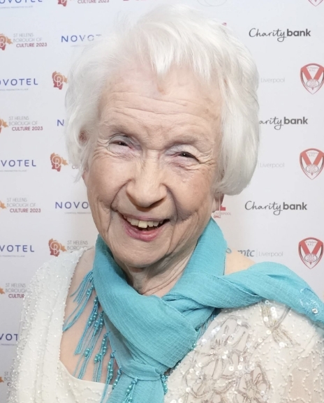 Elsie Kelly smiles at a public event in an image shared in a post dated 22 April 2026, as tributes pour in following the beloved "Benidorm" star's passing at 89. | Source: X/YoungJames34