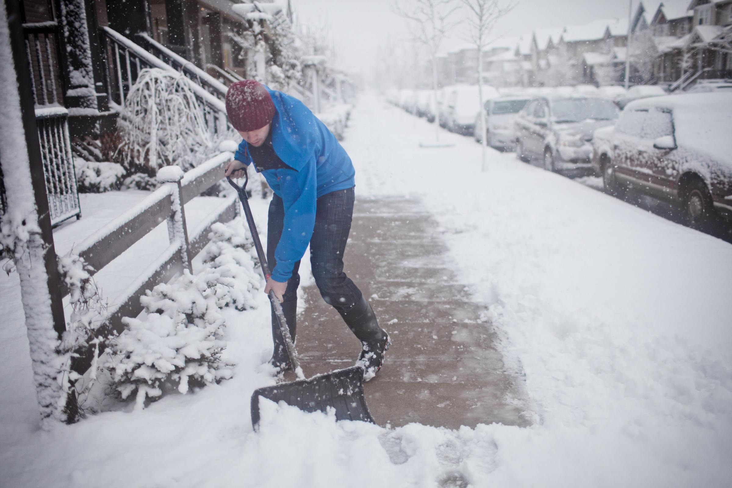 A man shovels the sidewalk outside of his suburban house during a snowstorm, dated July 9, 2015 | Source: Getty Images