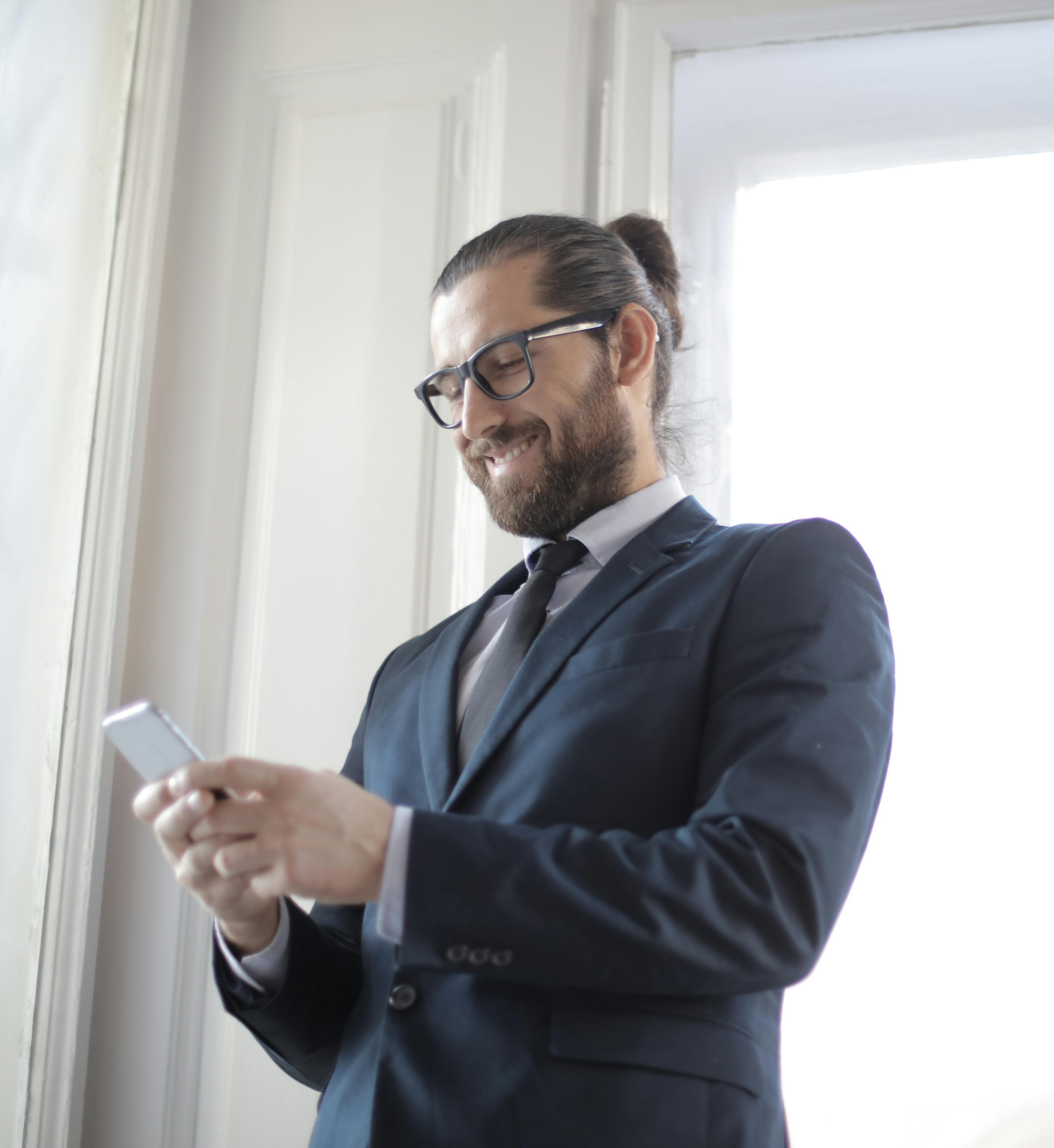 A man smiling at his phone | Source: Pexels